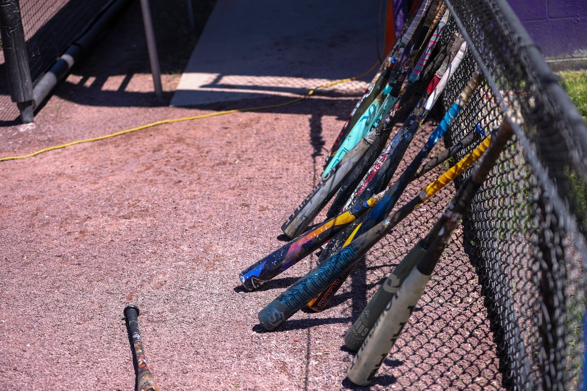 baseball bats on warning track outside dugout during practice at serpico stadium