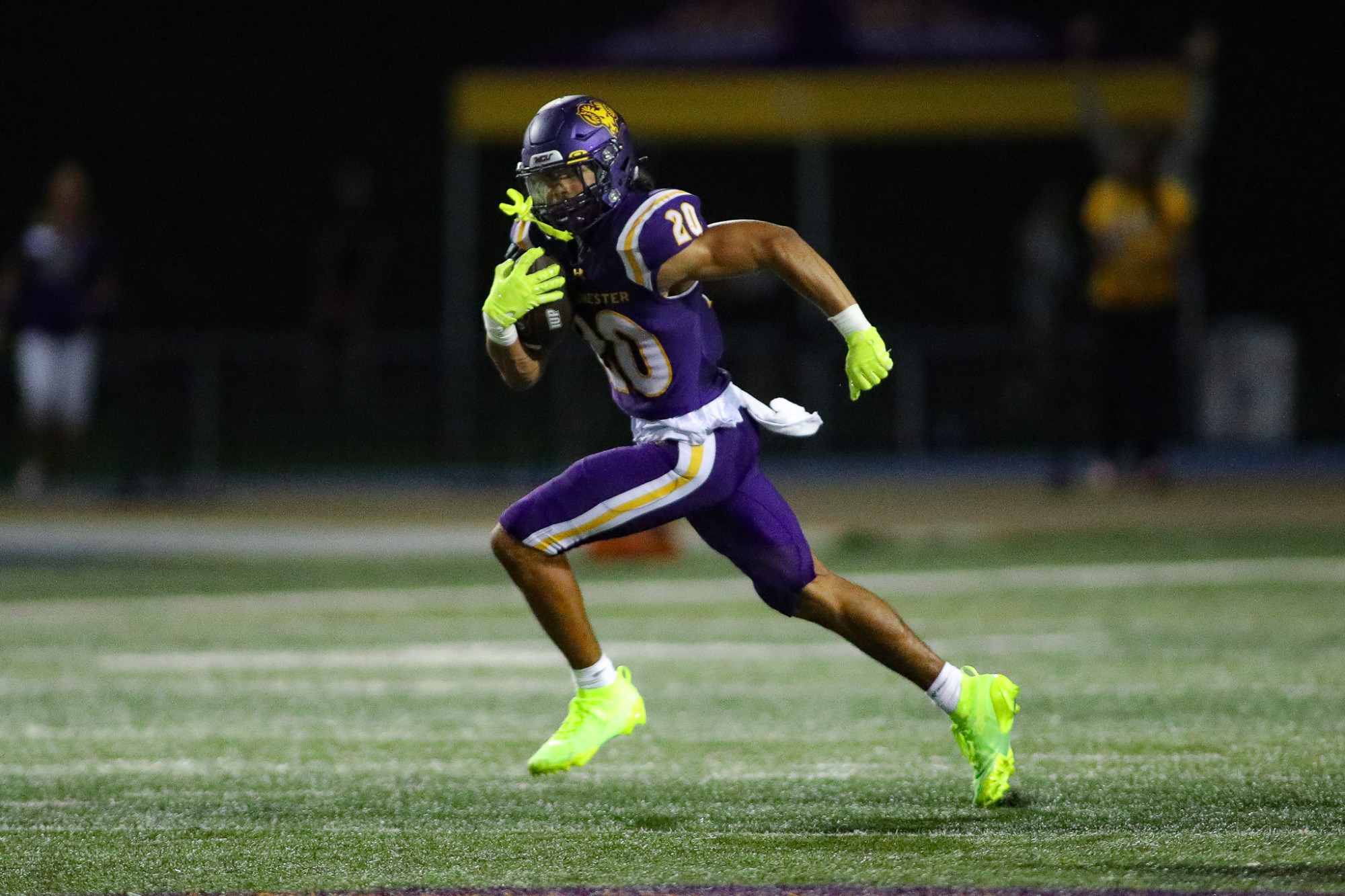 Bryan Anderson races 66 yards with the ball after a blocked FG attempt at night inside Farrell Stadium. He is wearing West Chester's purple uniforms with purple pants and purple helmet while wearing his green highlighter colored gloves and spikes.