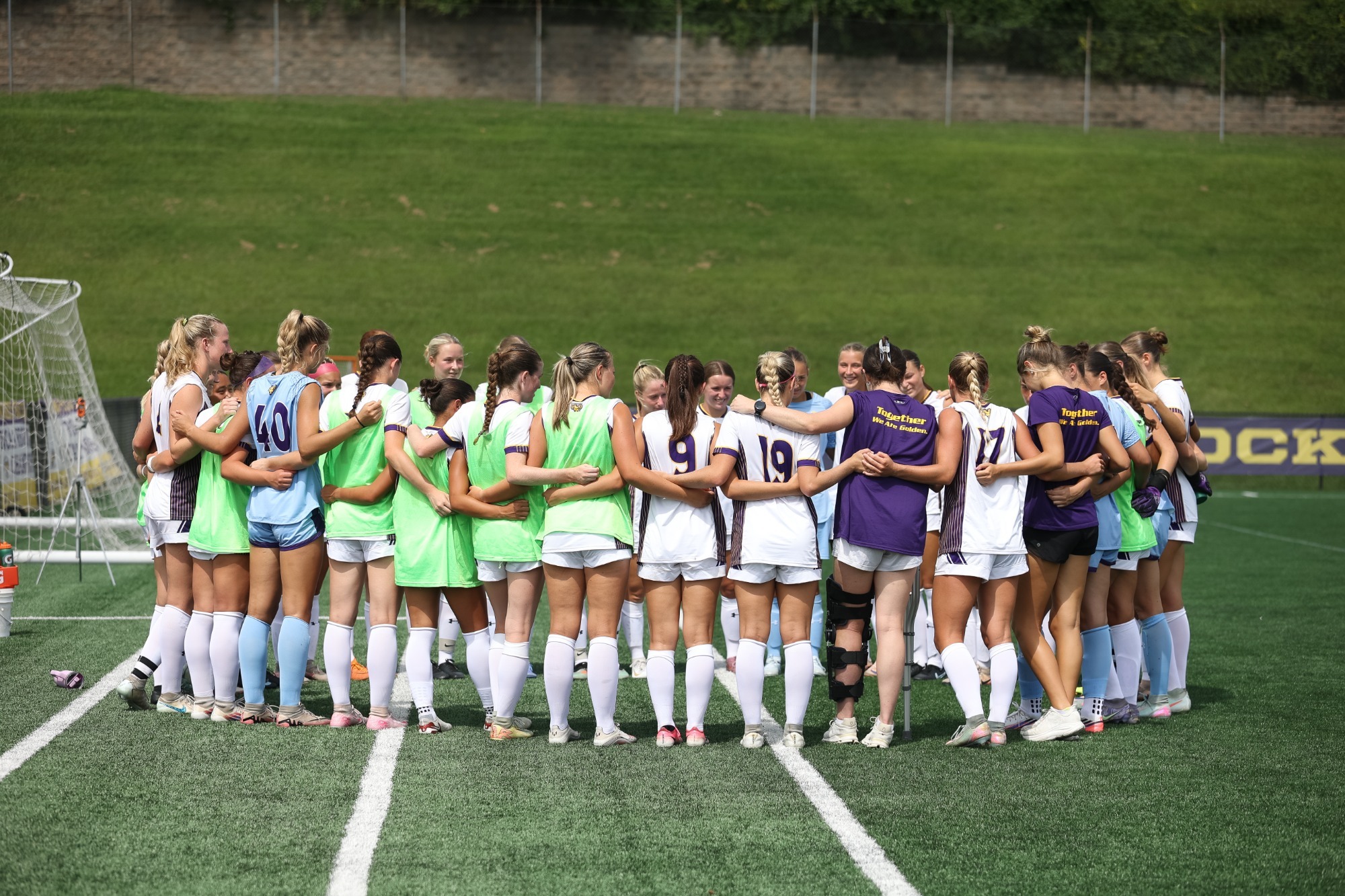 WOMEN'S SOCCER TEAM HUDDLES ON THE SIDELINE AT THE END OF HALFTIME VS LACKAWANNA WEARING HOME WHITE TOP AND WHITE SHORT UNIFORMS