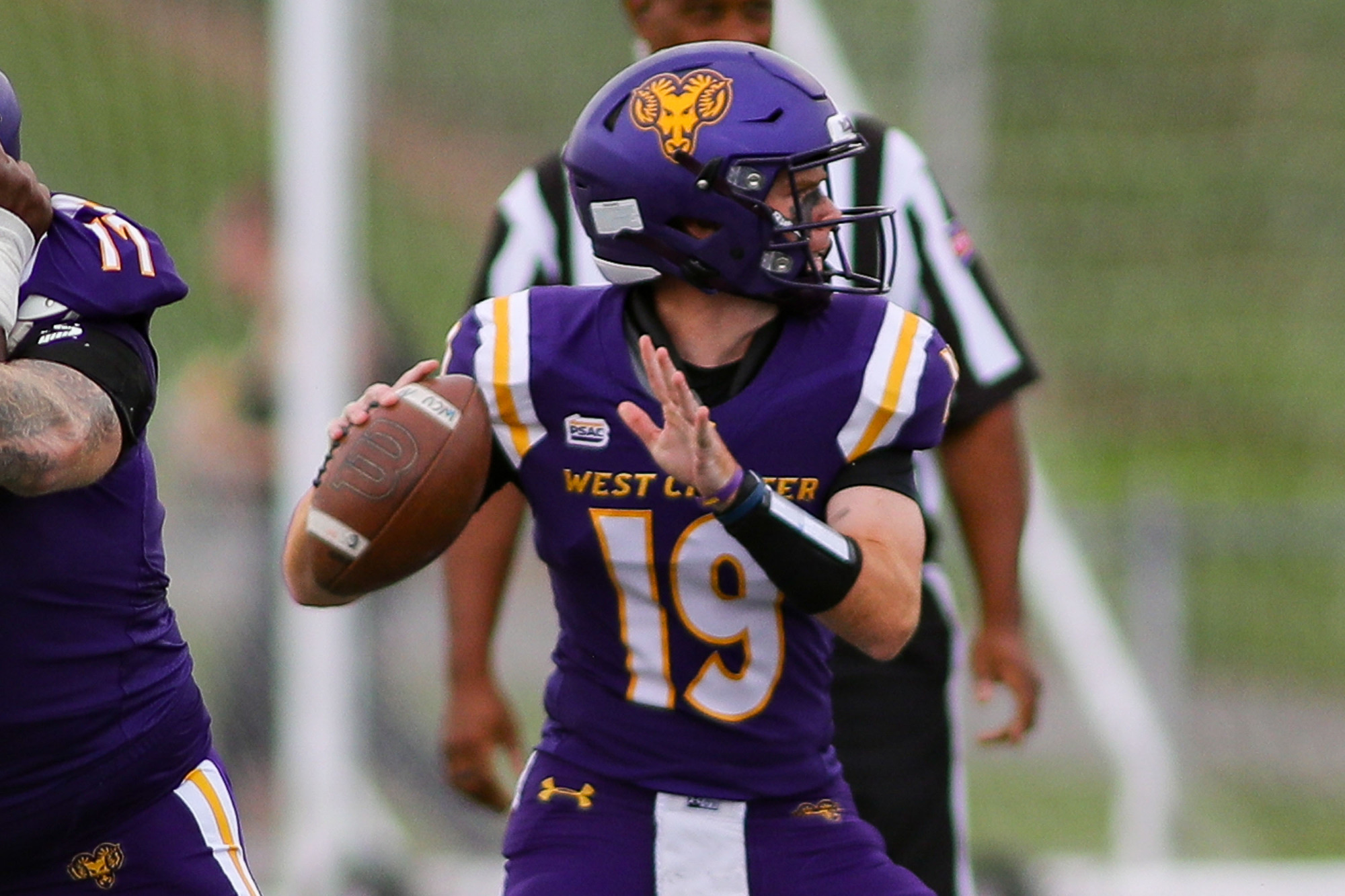 Colin O'Sullivan looks to pass against IUP in West Chester's home jersey's with purple pants and purple helmet.