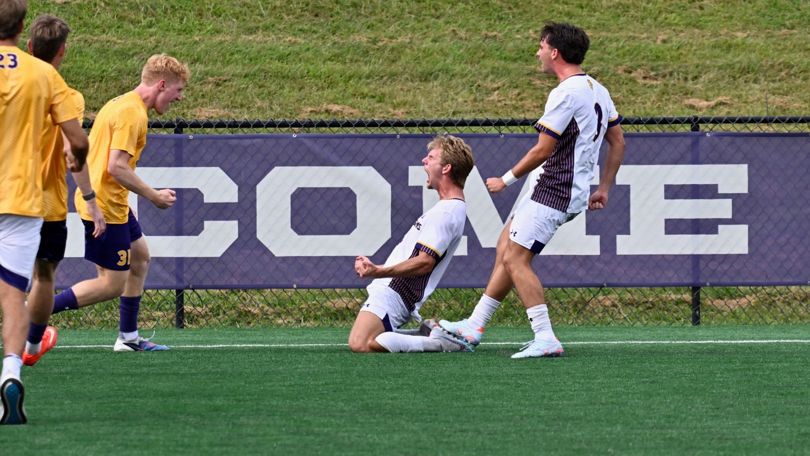 Lukas Bentsen wearing home white on white celebrates the eventual game-winning goal with teammates, including Caleb Addalia in yellow on Saturday afternoon