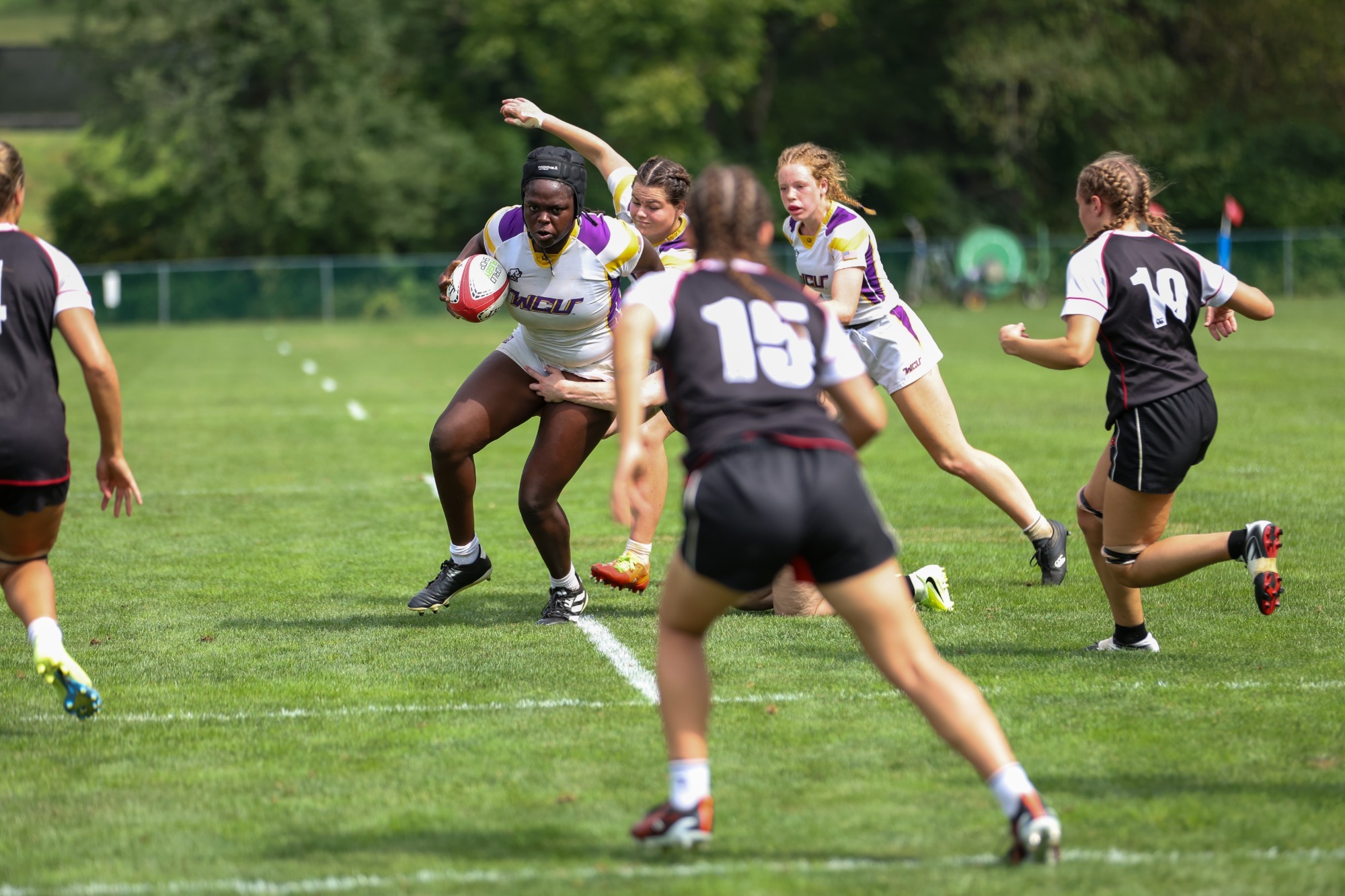 Christelle Adikpeto wearing home white on white kit and black headgear runs through a tackle against Davenport in WCU home opener on 9-12