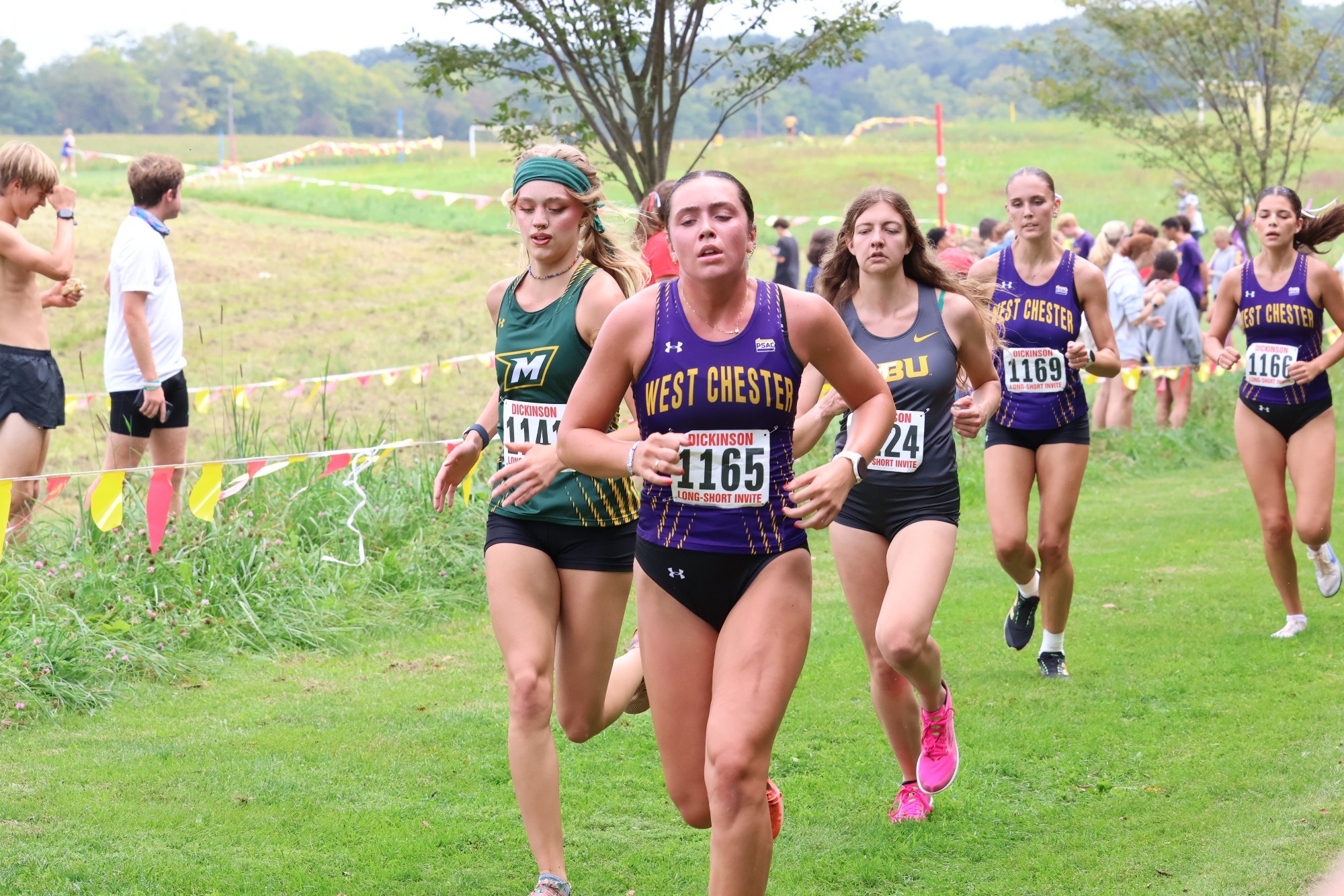WOMEN'S CROSS COUNTRY GROUP OF WCU RUNNERS WEARING PURPLE AND GOLD RACING TOPS RUNNING AT DICKINSON LONG-SHORT