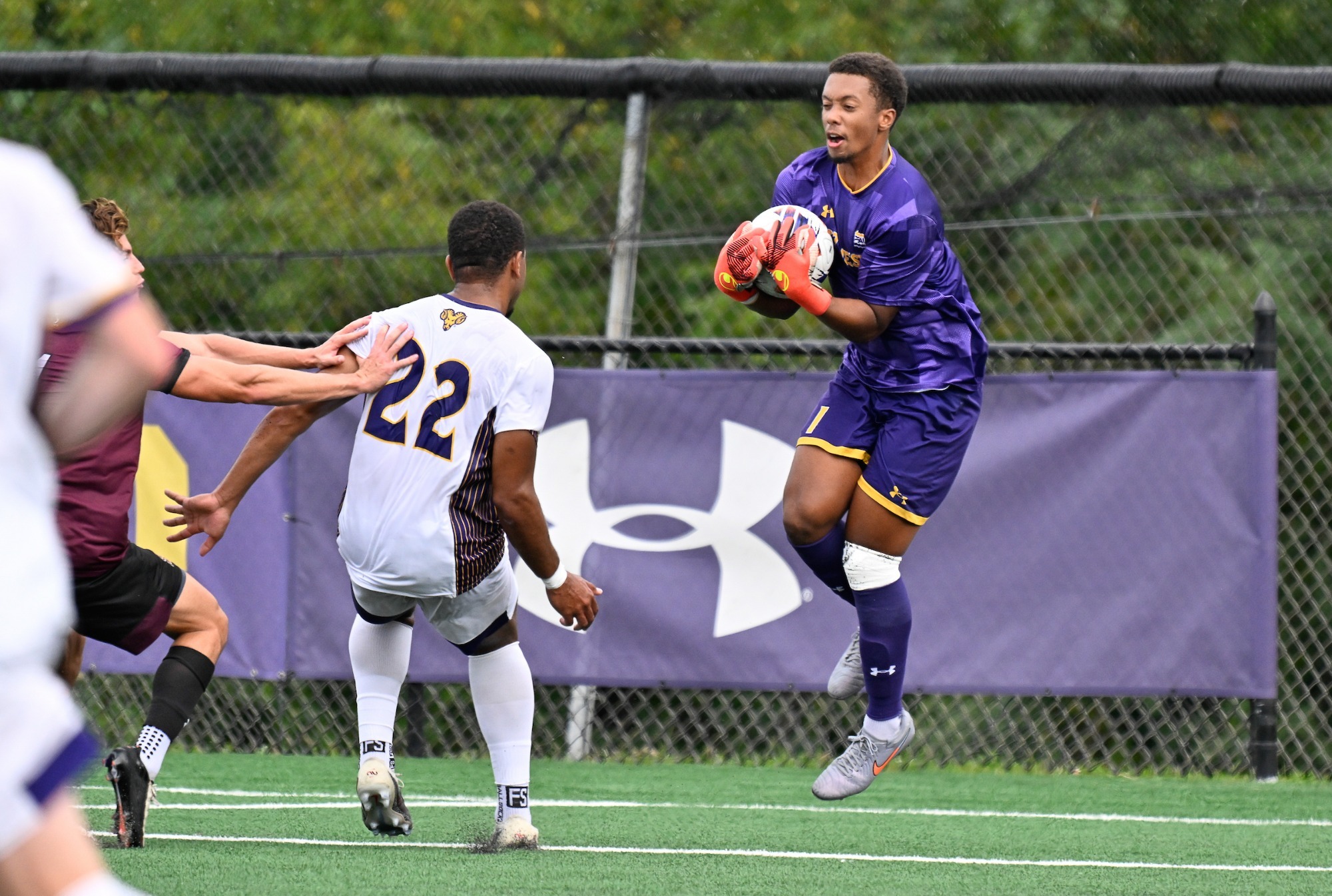 JADEN HOWARD WEARING PURPLE KEEPER UNIFORM JUMPS TO COLLECT LOOSE BALL IN BOX AGAINST BLOOMSBURG IN FRONT OF WCU DEFENDER TYLER VAGNER
