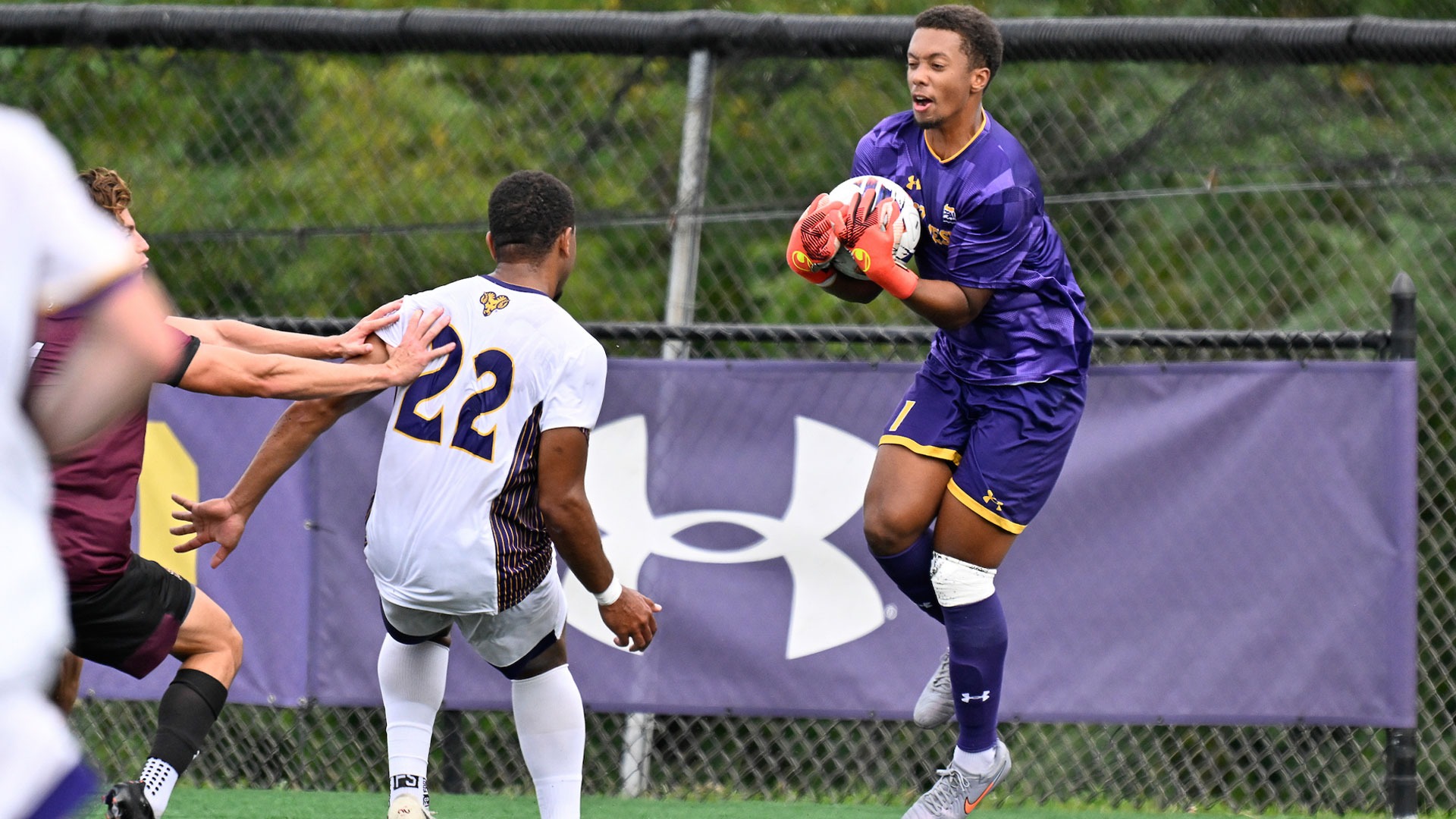 JADEN HOWARD WEARING PURPLE KEEPER UNIFORM JUMPS TO COLLECT LOOSE BALL IN BOX AGAINST BLOOMSBURG IN FRONT OF WCU DEFENDER TYLER VAGNER