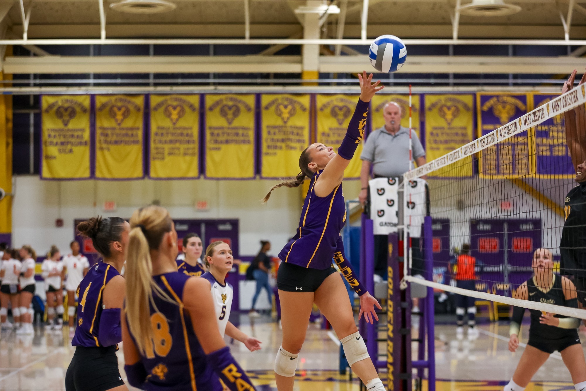 BROOKE FORESTER GOES UP FOR AN ATTACK VS WVSU. FORESTER WEARING PURPLE AND GOLD SLEEVELESS JERSEY WITH PURPLE ARM SLEEVES THAT SAY GOLDEN RAMS IN GOLD TEXT