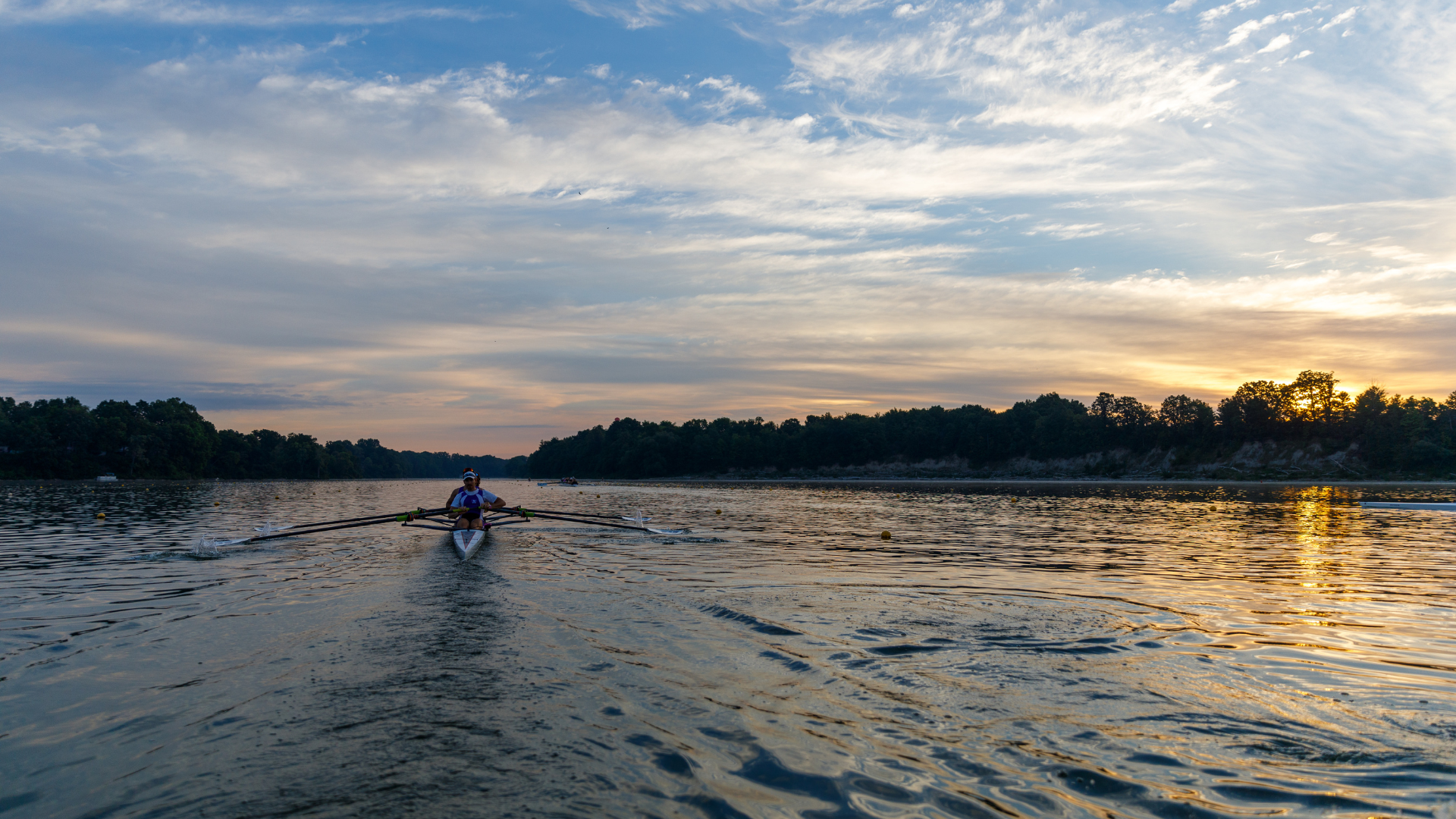 FISU Rowing 2026 Release: Photo of Mustangs rowers on a boat on Fanshawe Lake. Sunset.