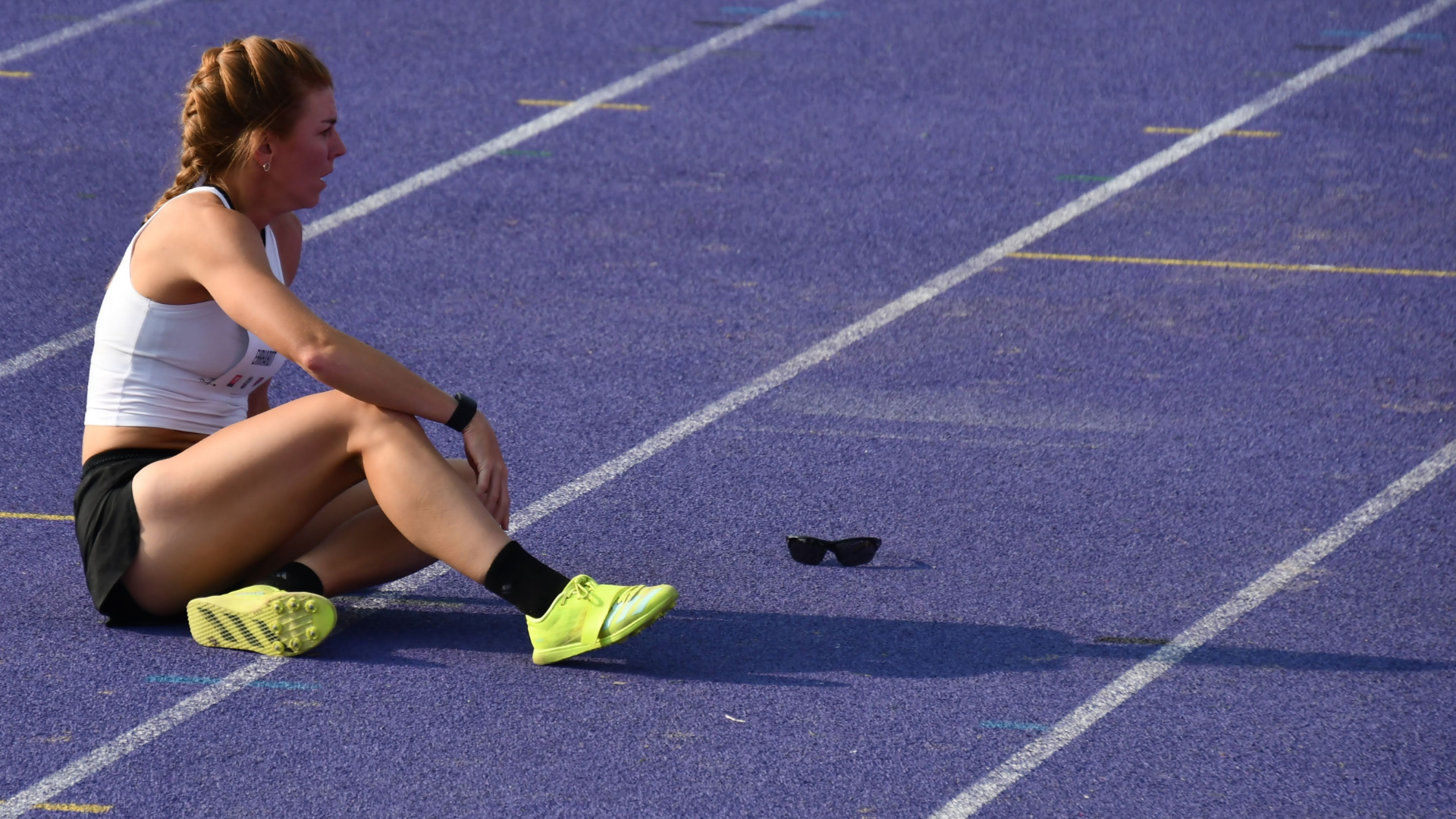 Woman sitting on track with sunglasses on the track beside her