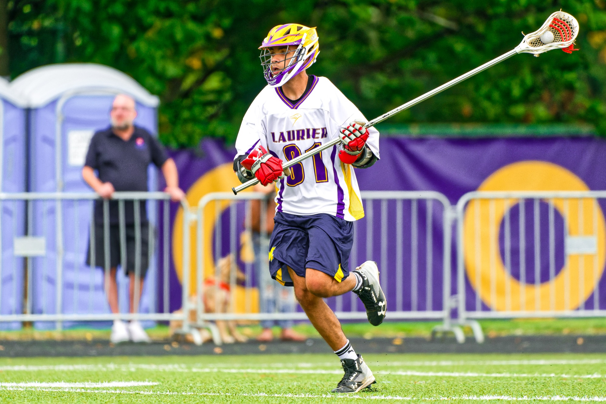 Laurier men's lacrosse player carries the ball up field