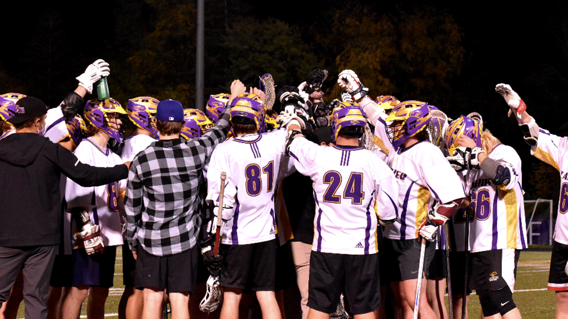 Laurier's men's lacrosse team gathered in a huddle with their gloves raised for a cheer