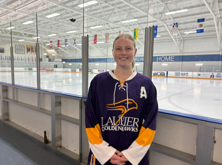 Leah Partridge stands in front of the ice rink
