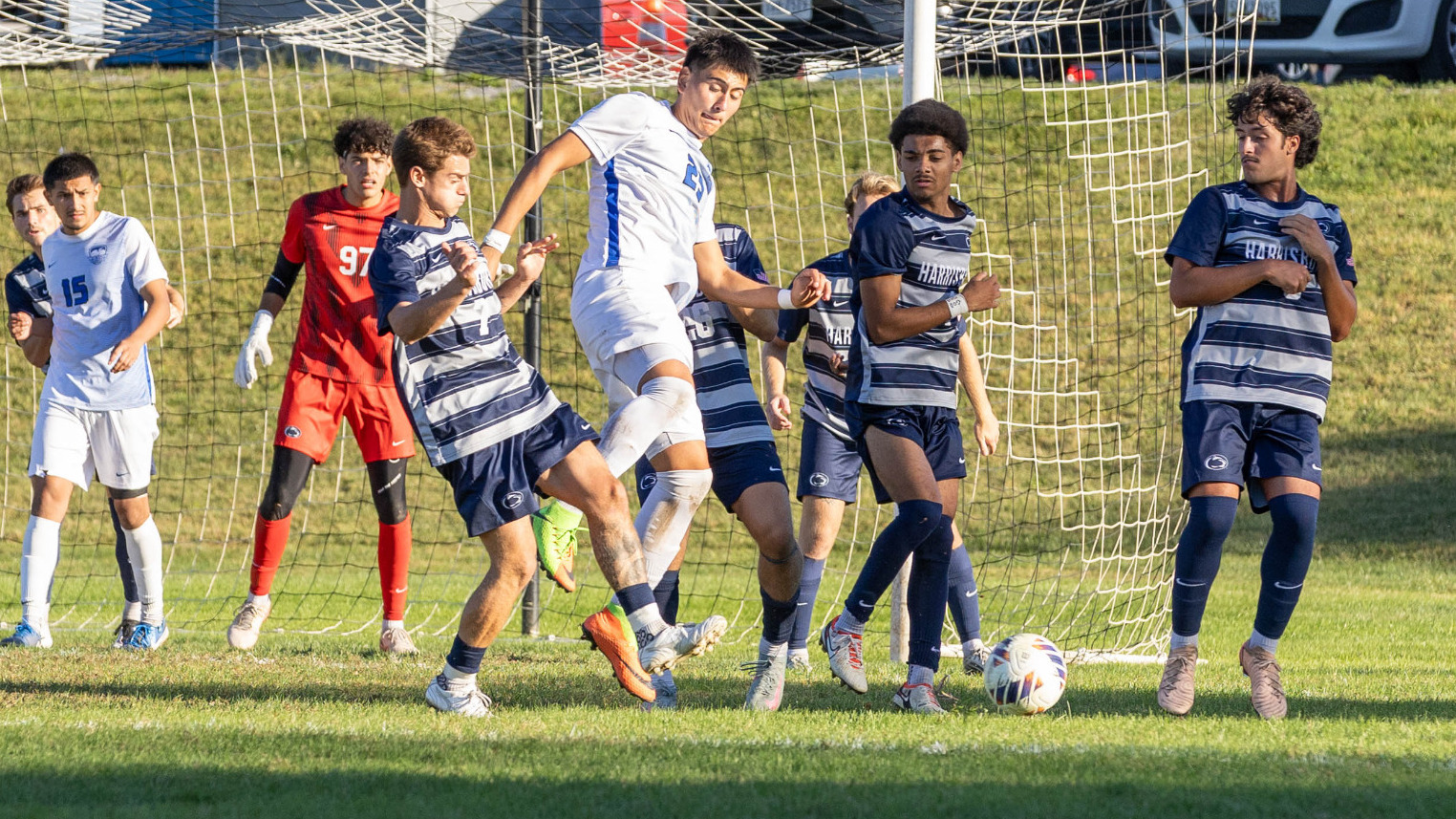 Lenin Cinco kicks the ball surrounded by a bunch of players in front of the goal