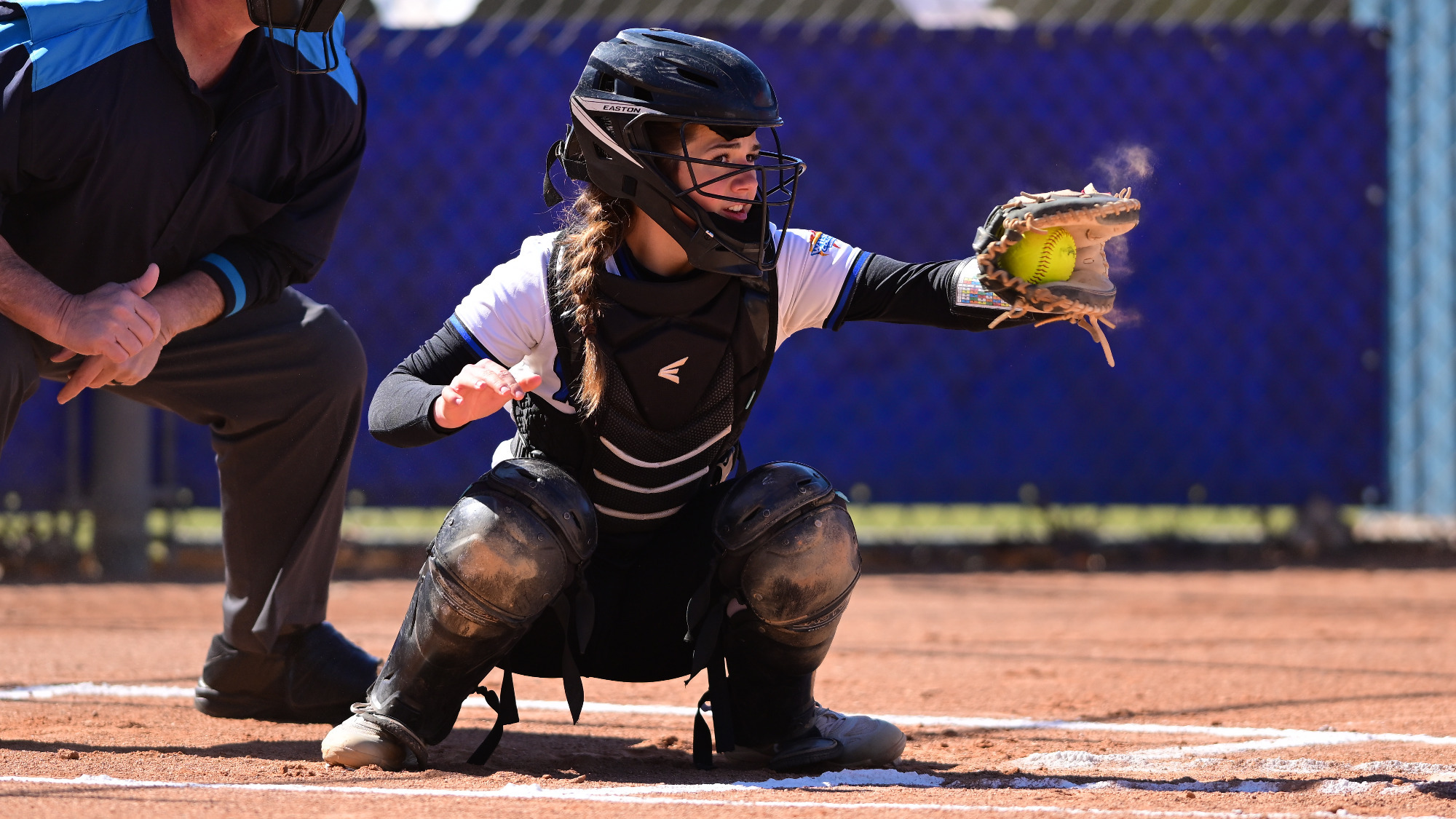 Jenna Weaver catches a pitch and looks at a runner on first base.