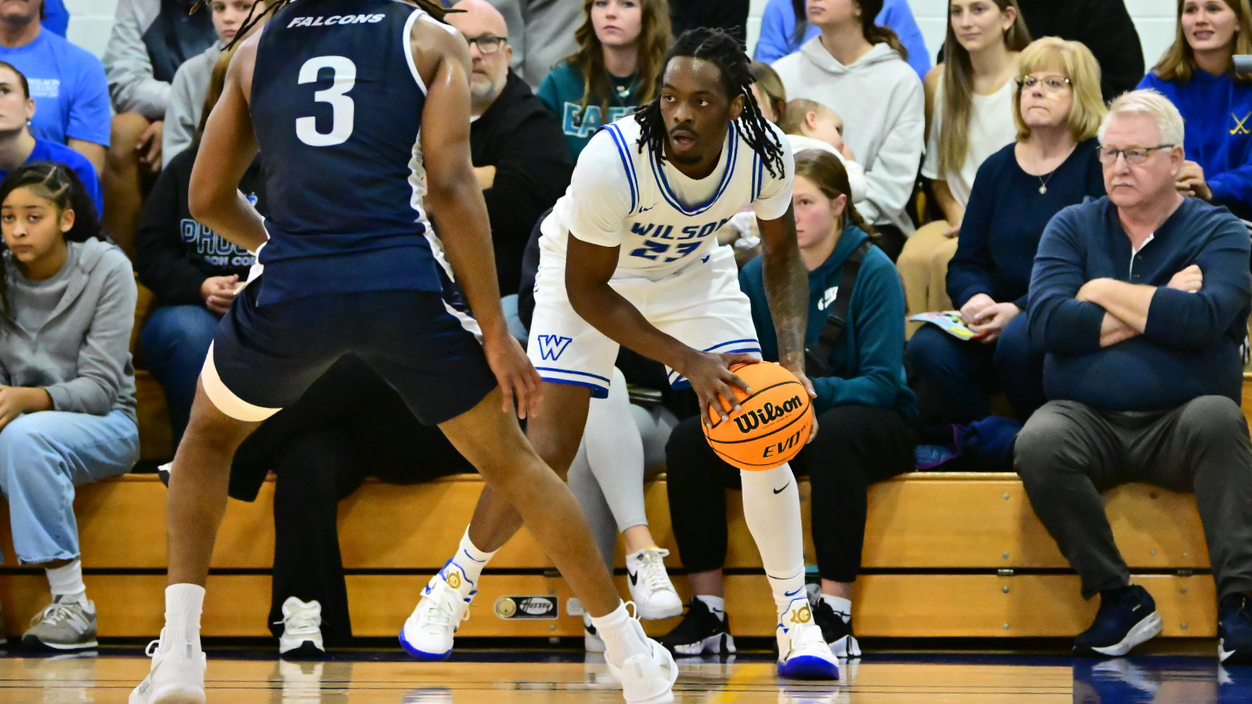 Armani Jones looks for an open player before driving the baseline while guarded by a defender.