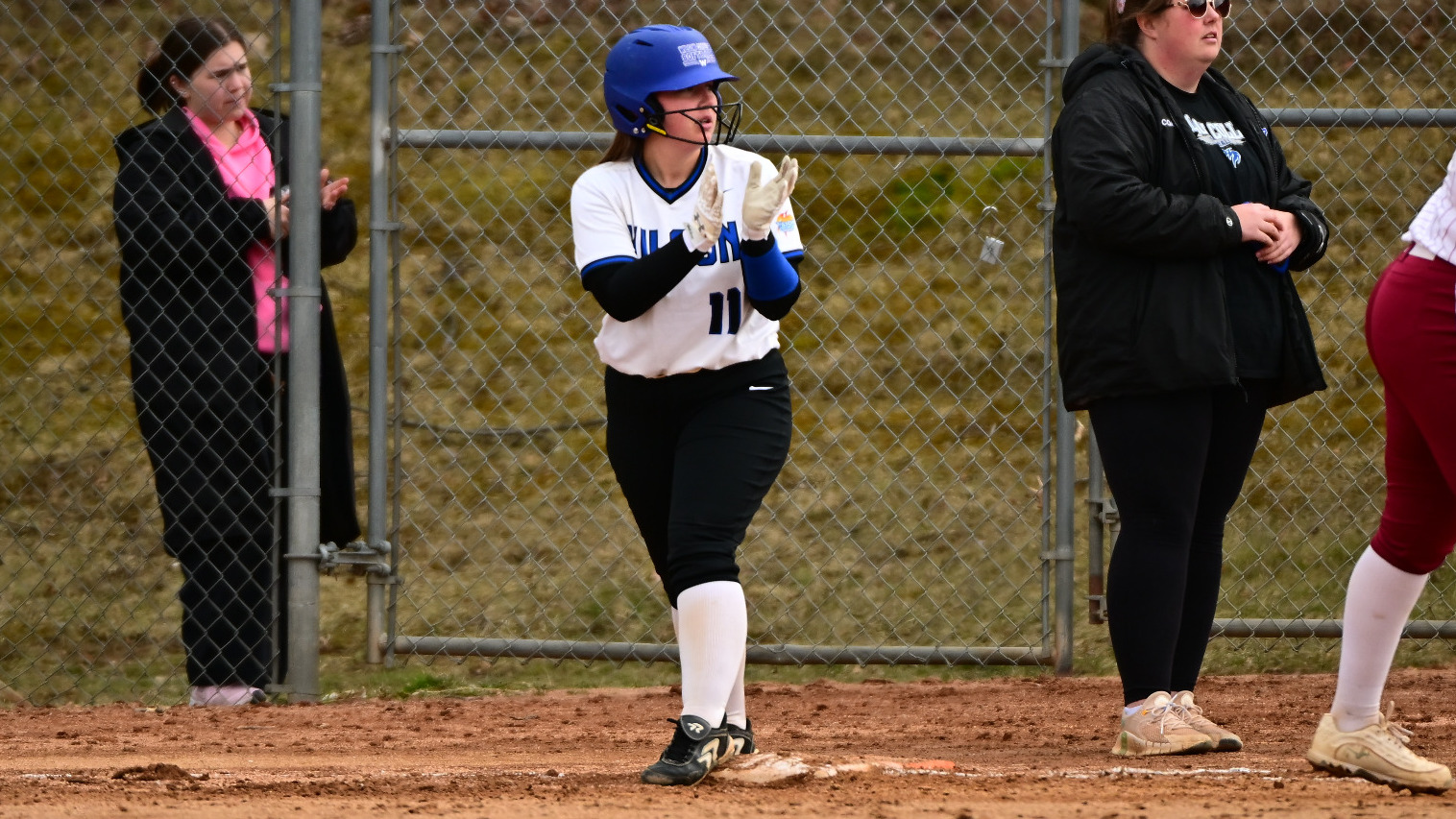 Sydney Hartle claps while standing on first base waiting to run to second.