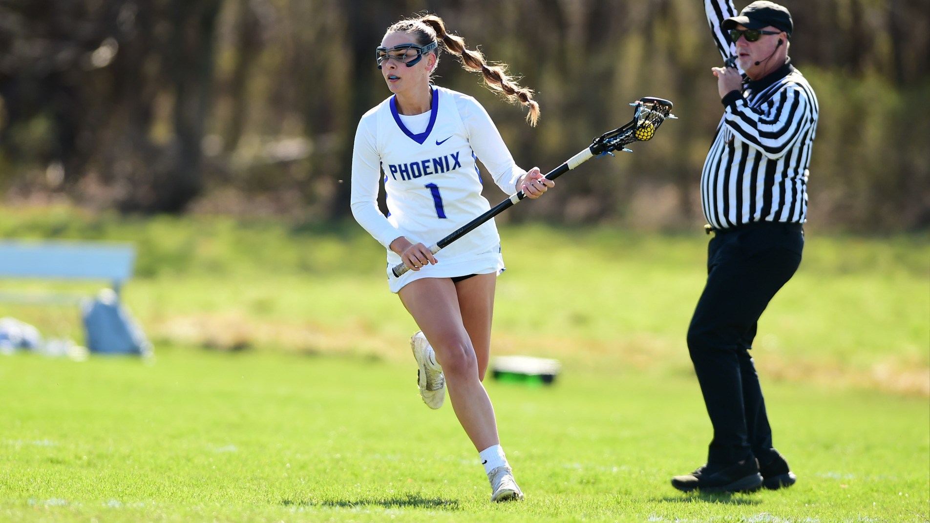 Alaina Marek runs down the field looking for an open player with a referee standings beside her.