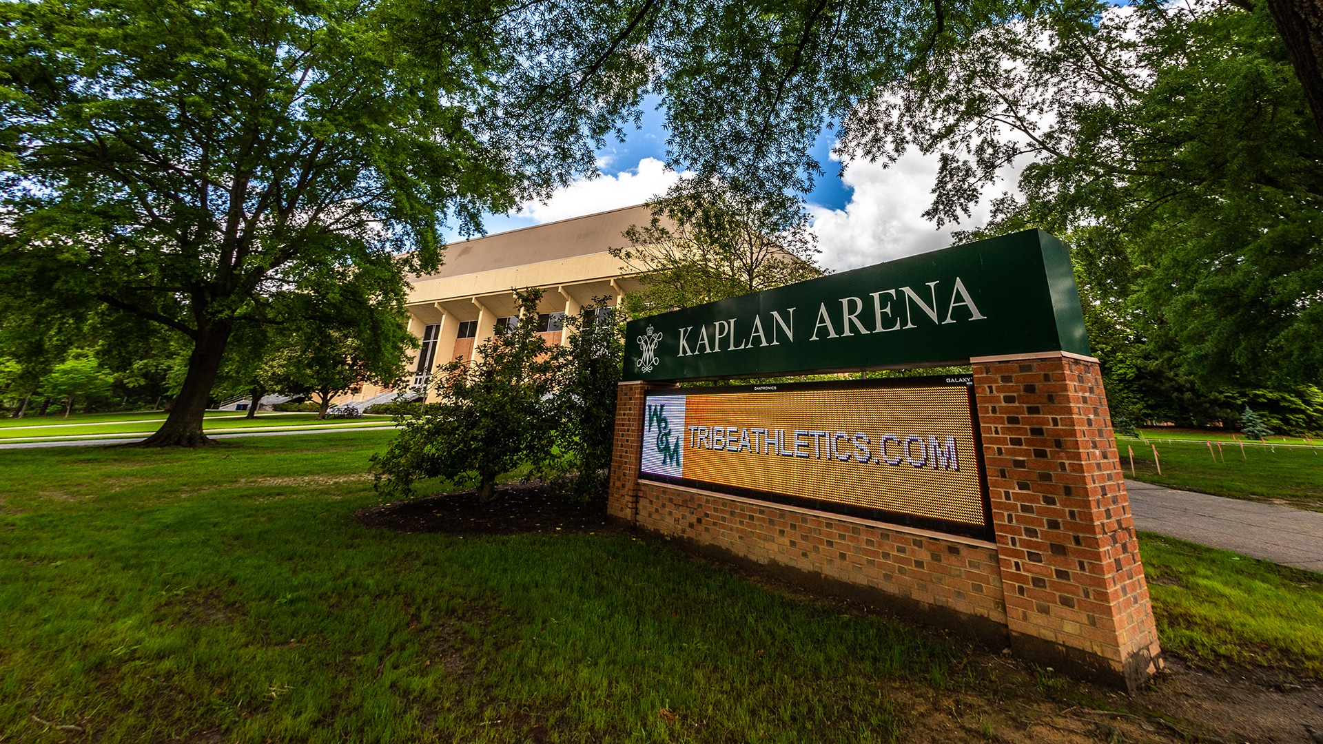 Angled photo of the outside of Kaplan Arena with the electronic sign on the right and Kaplan in the background. 