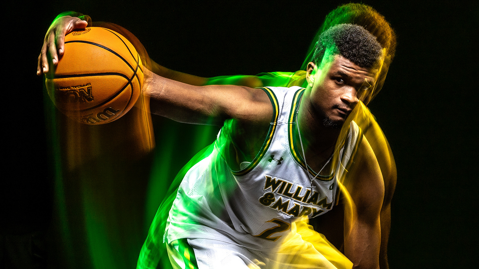 Chase Lowe dribbles a ball during a photo shoot with lighting efforts on him and in the background. 