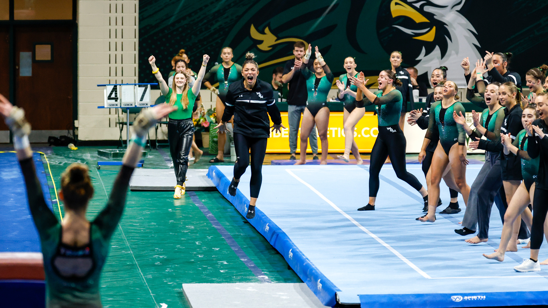 Members of the W&M women's gymnastics team celebrate a successful vault routine duirng a meet against West Chester at Kaplan Arena.