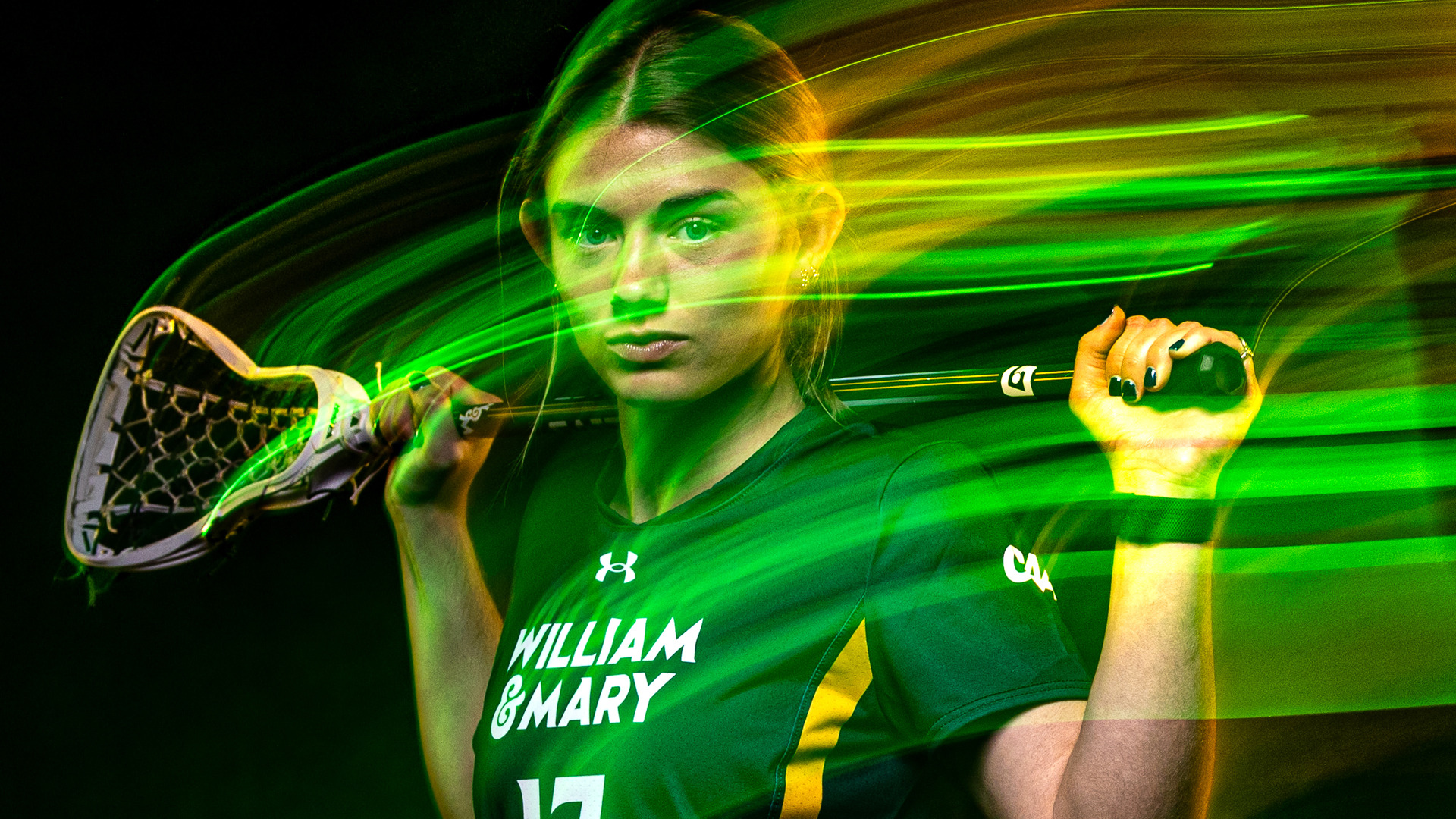 Maresa Moyer stands with a lacrosse stick with green & gold light streaks 