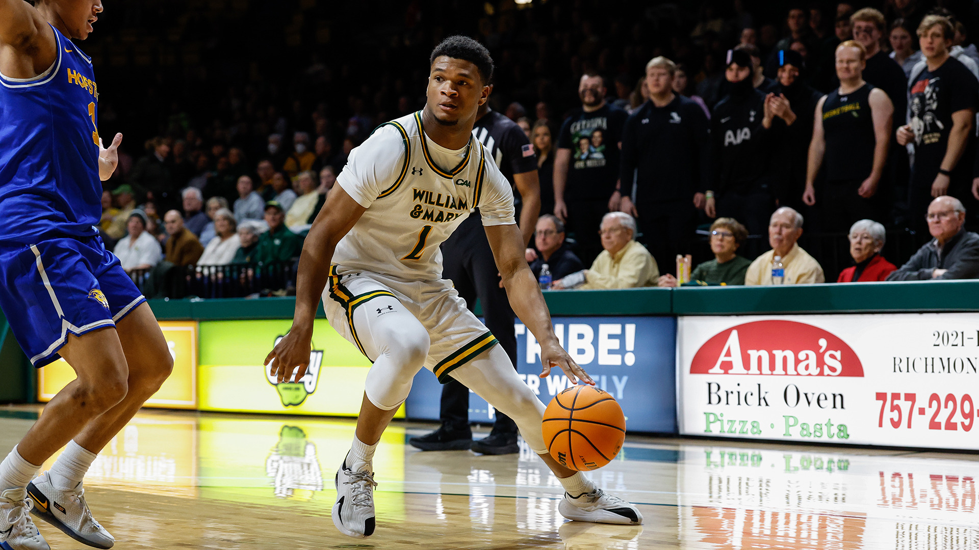 Chase Lowe dribbles along the baseline against Hofstra with the student section in the background. 