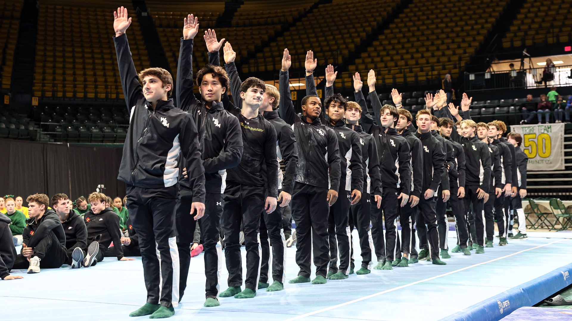 Members of the W&M men's gymnastics team stand to be recognized following a meet at Kaplan Arena