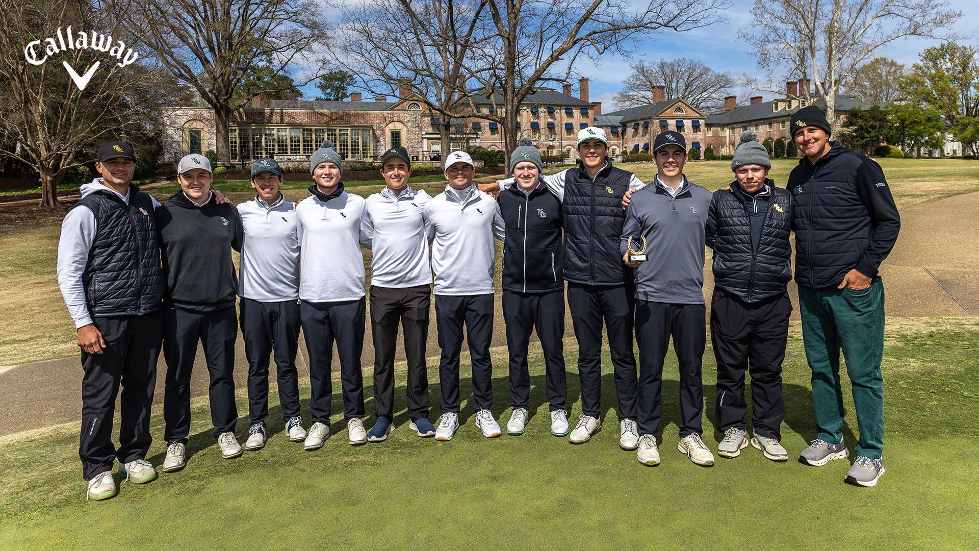 The Tribe men's golf team stands in a line to commemorate winning the Golden Horseshoe Intercollegiate, with Eli Felty (third from right) holding the winning trophy. The Callaway logo is in white in the upper left corner. 