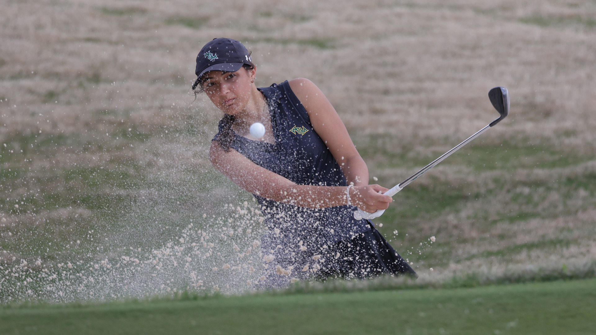 Jennifer Osborne hits out of a bunker with sand flying in the air during a practice round at the Carolina Challenge Cup. 