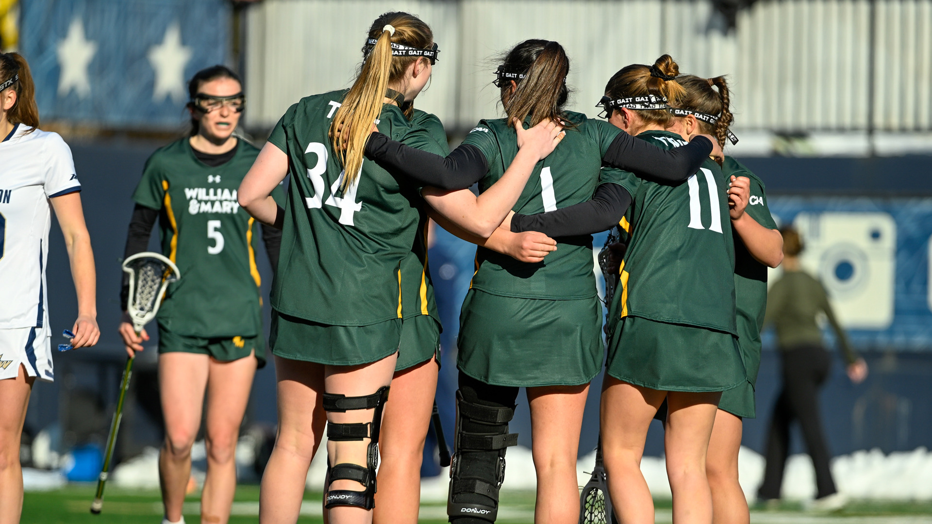 Members of the W&M lax team stand in a huddle during a game