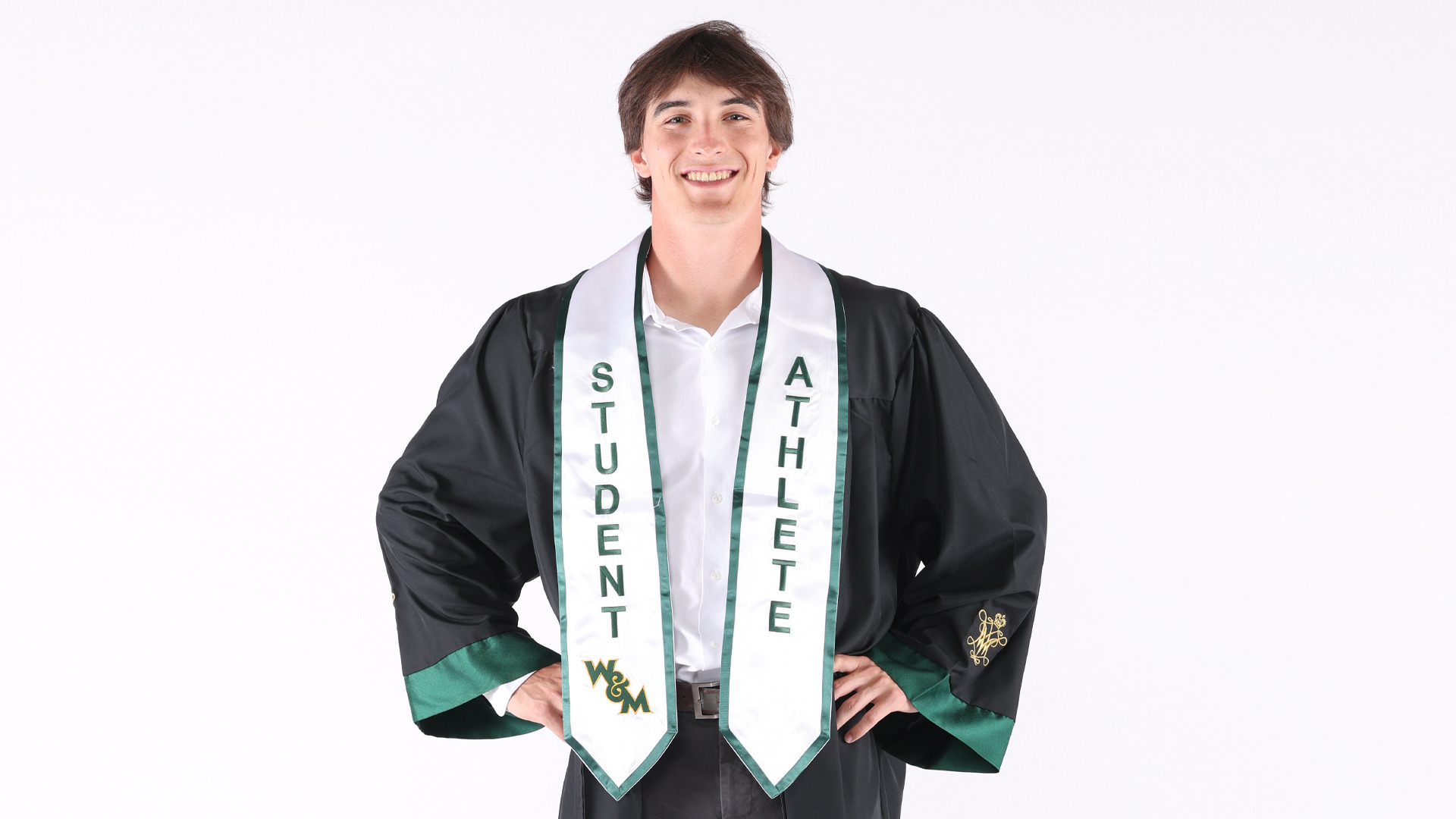 Owen Pierce poses for a graduation photo, wearing dress closes along with gown and Student-Athlete stole following his four years at W&M as a pitcher. He earns his degree in business analytics and data science with a concentration in sustainability. 