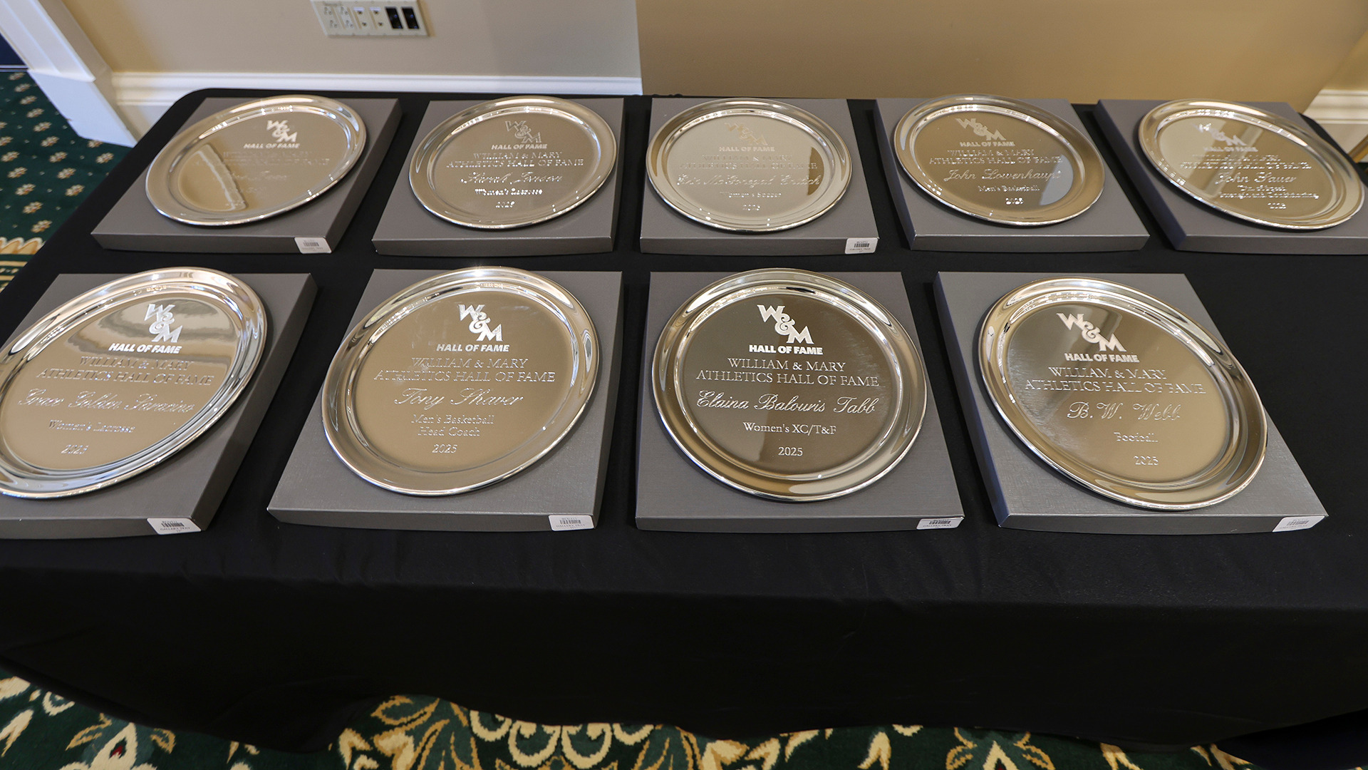The Silver Hall of Fame Plates for the Class of 2025 sit on a table prior to the induction ceremony at the Alumni House. 