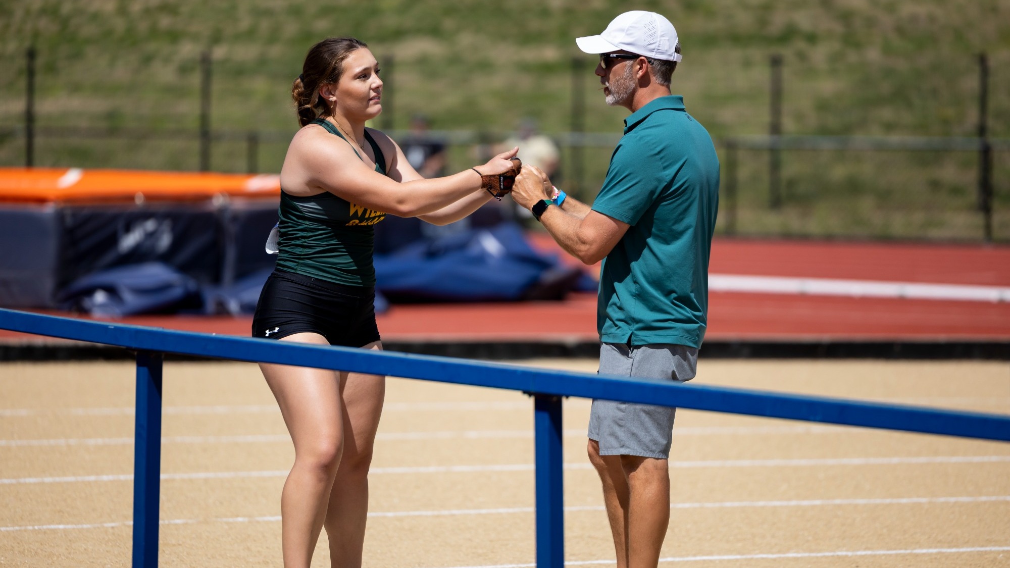 Amelia Bawcombe and Alex Heacock fist bumping each other at an outdoor track meet