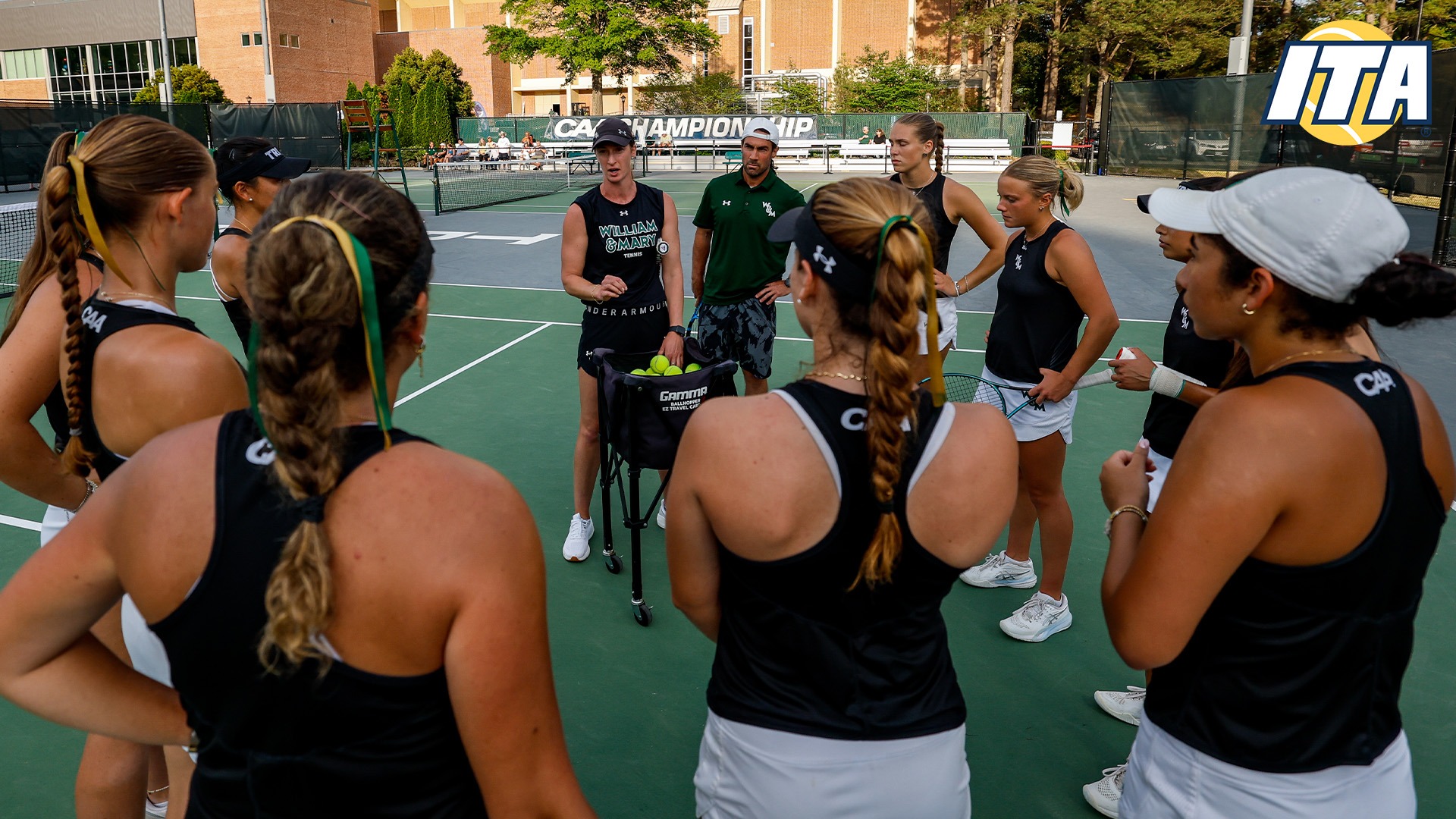 William & Mary women's tennis huddled up on the tennis court with the ITA logo in the top right