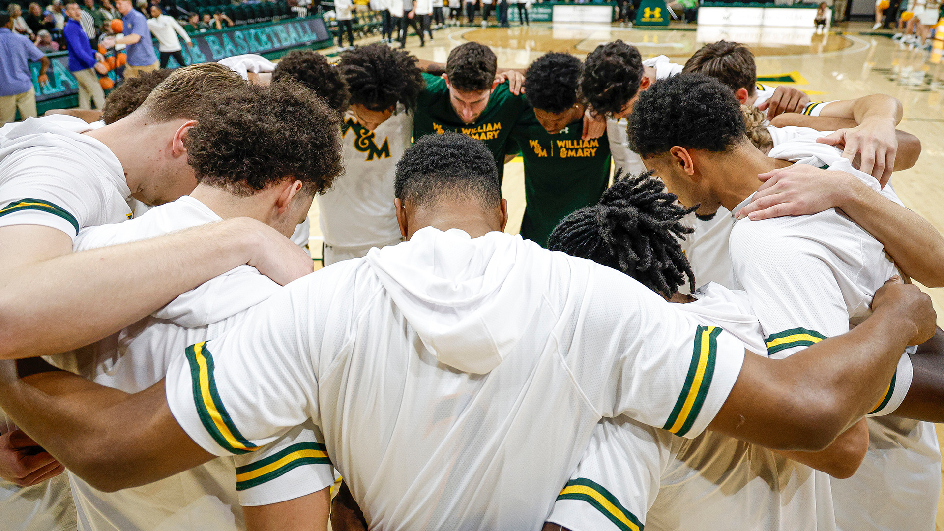 The William & Mary men's basketball team huddles up with arms on shoulders prior to the season opener against Georgian Court in 2025. 
