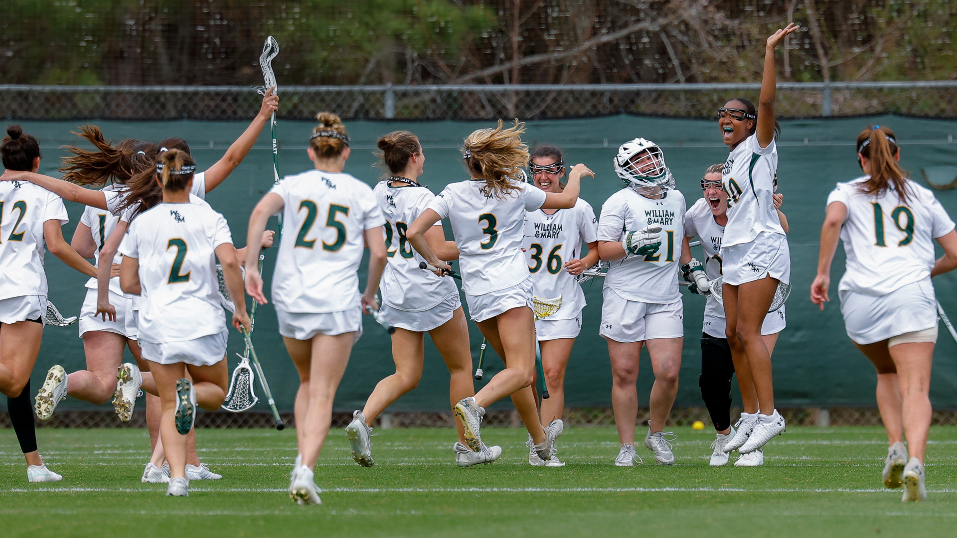Members of the W&M lacrosse team celebrate on the field at Martin Family Stadium after a victory.