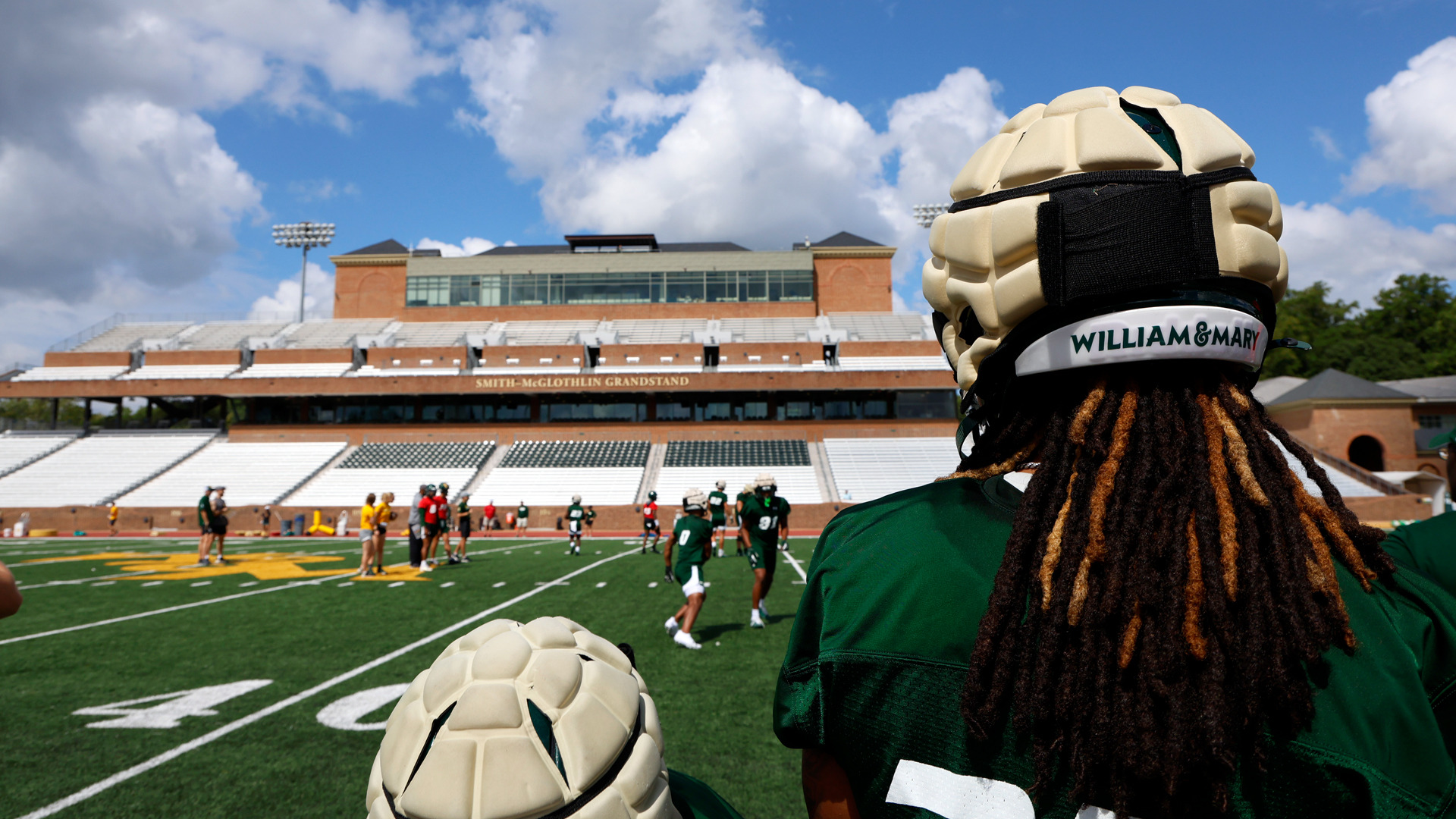 Looking over a W&M football player's shoulder across the field towards the Zable Stadium grandstand