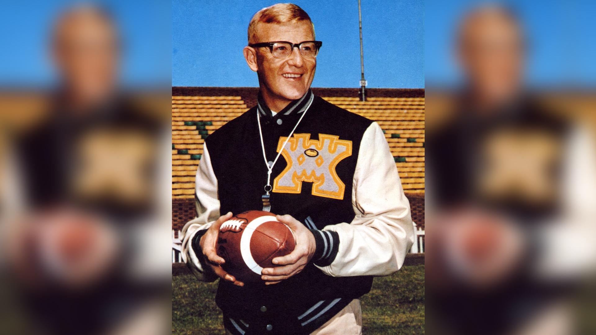 Lou Holtz wearing a W&M letter jacket and holding a football