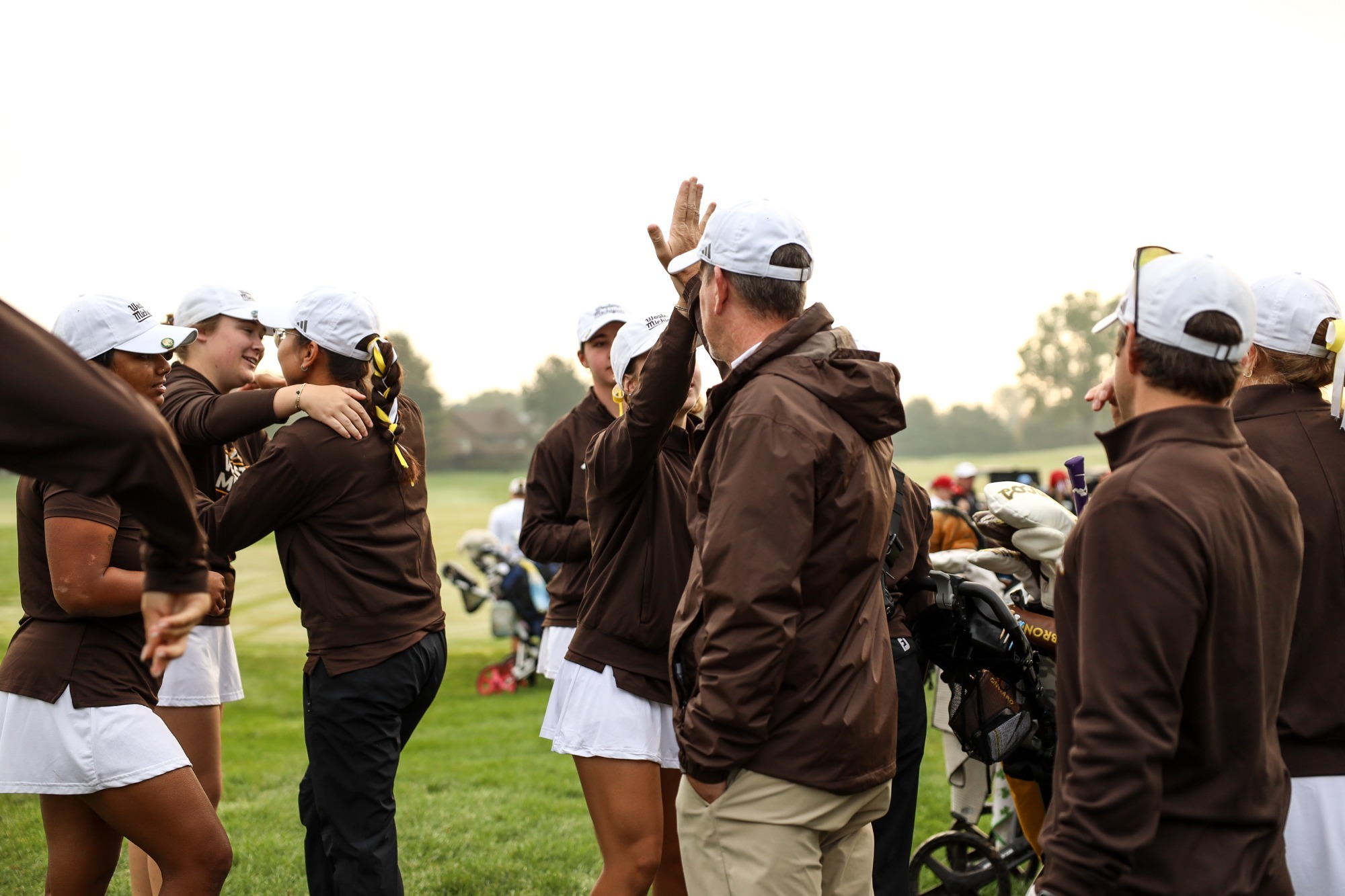 A Bronco women's golfer high fives Assistant Coach Chris Andrews before beginning the first round of the Bronco Fall Classic golf tournament