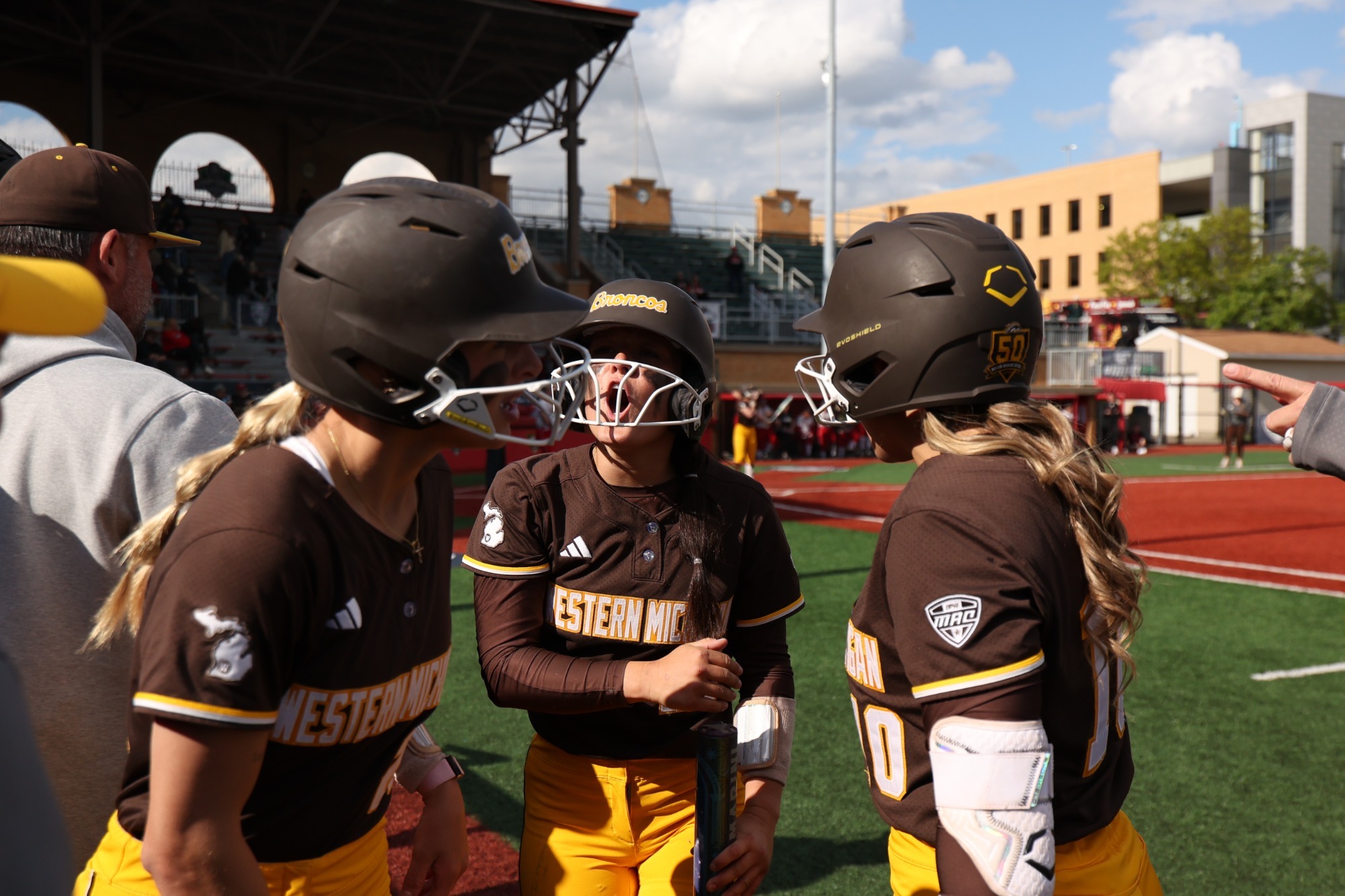 Hannah Herman, Bella Duncan, and Emily Lampela celebrate scoring a run by the Broncos dugout