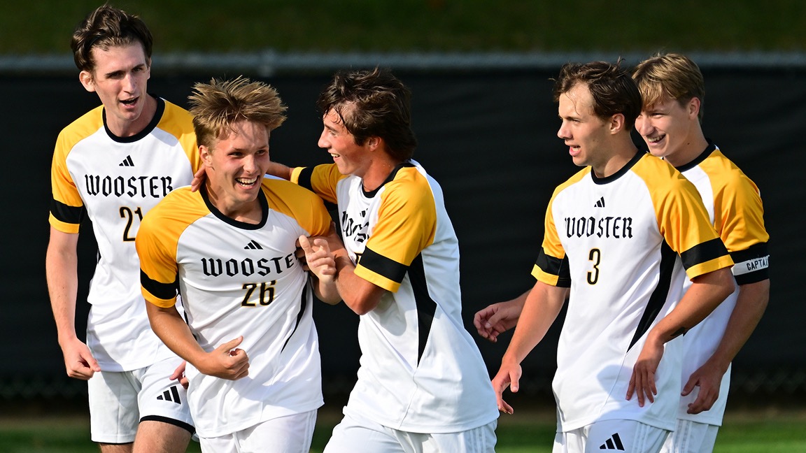 Five players from the soccer team are all smiles following a score