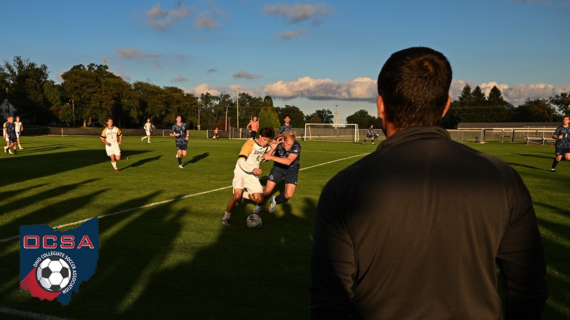 Coach Zidron, with his back facing the camera, watches play from the sideline