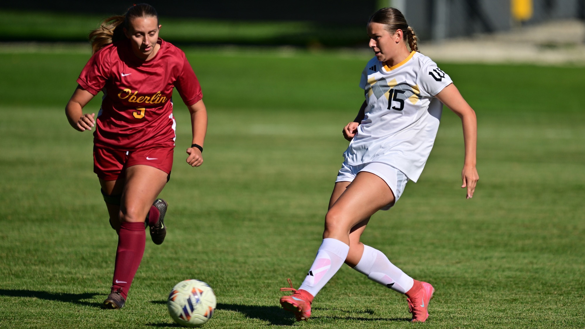 Paige Schulz goes to kick the ball with her left foot as a defender looks on
