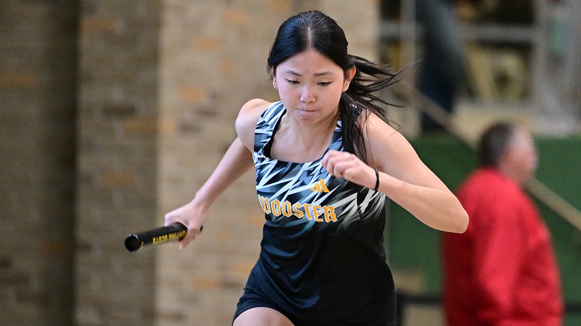 Claire Davis runs with a baton in an indoor meet