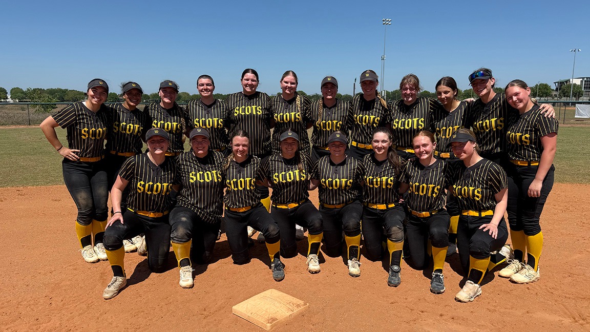 The softball team poses near second base after a successful spring trip