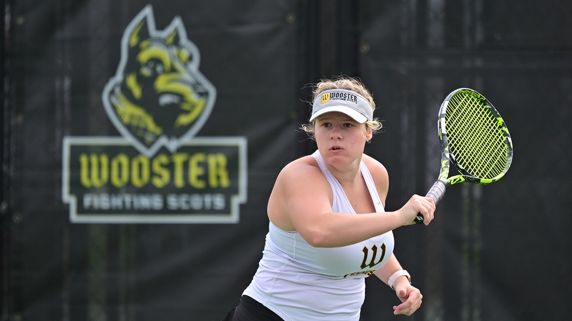 Elizabeth Meiners swings her racket with a picture of the Wooster logo behind her on the fence.