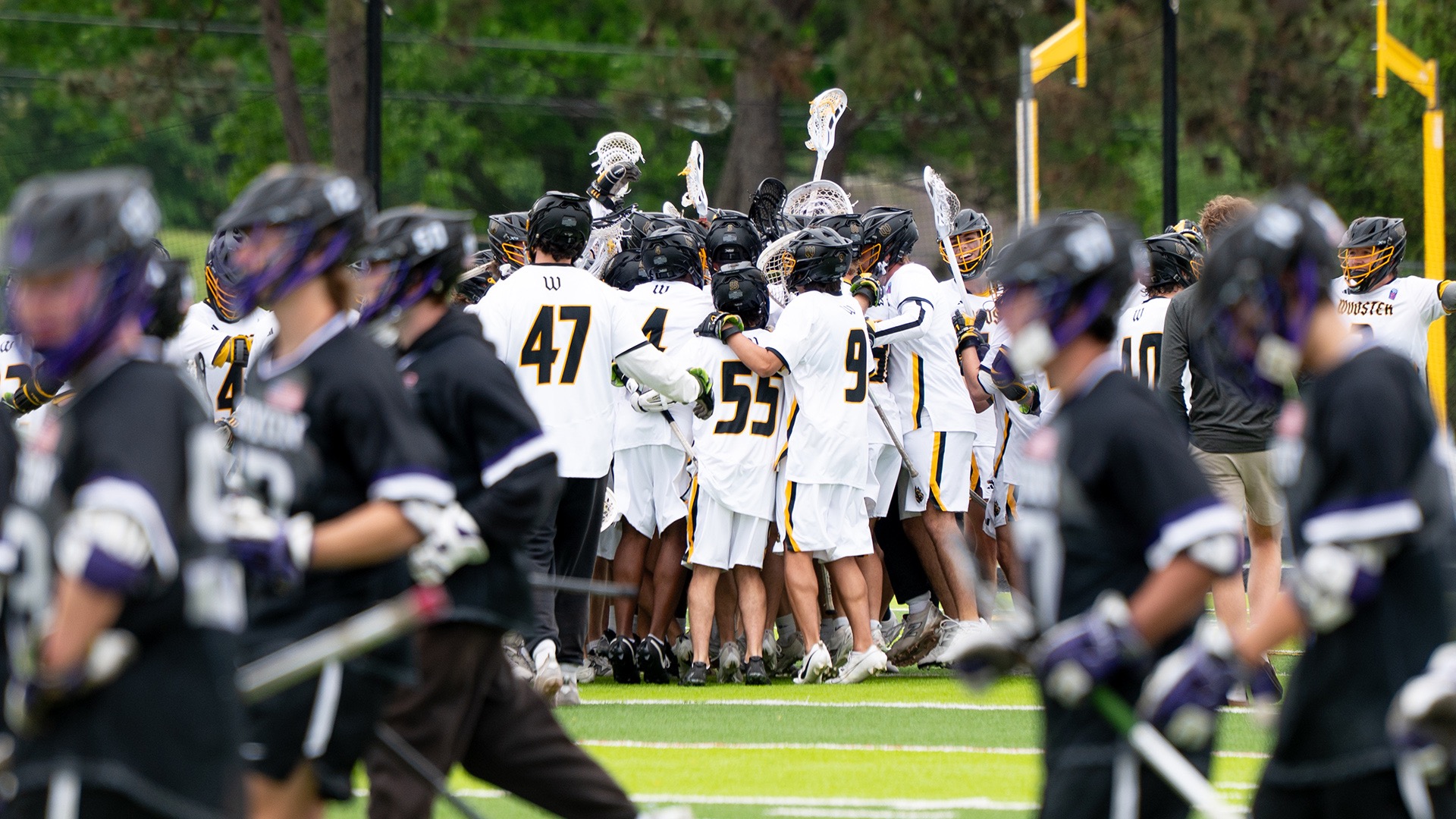 The men's lacrosse team celebrates in the background while in the foreground, Kenyon players run off the field
