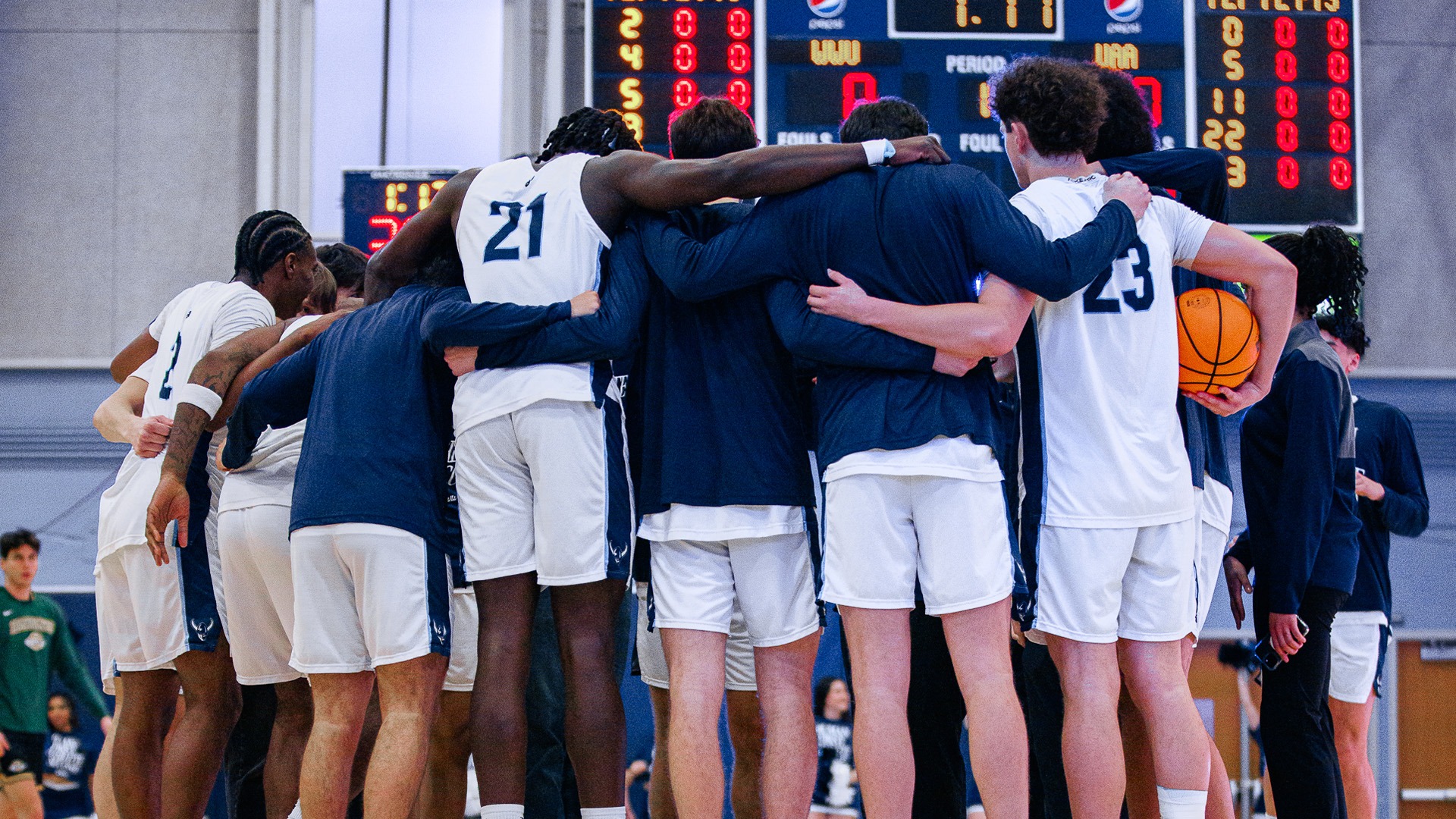 MBB Team Photo with group huddled near center court