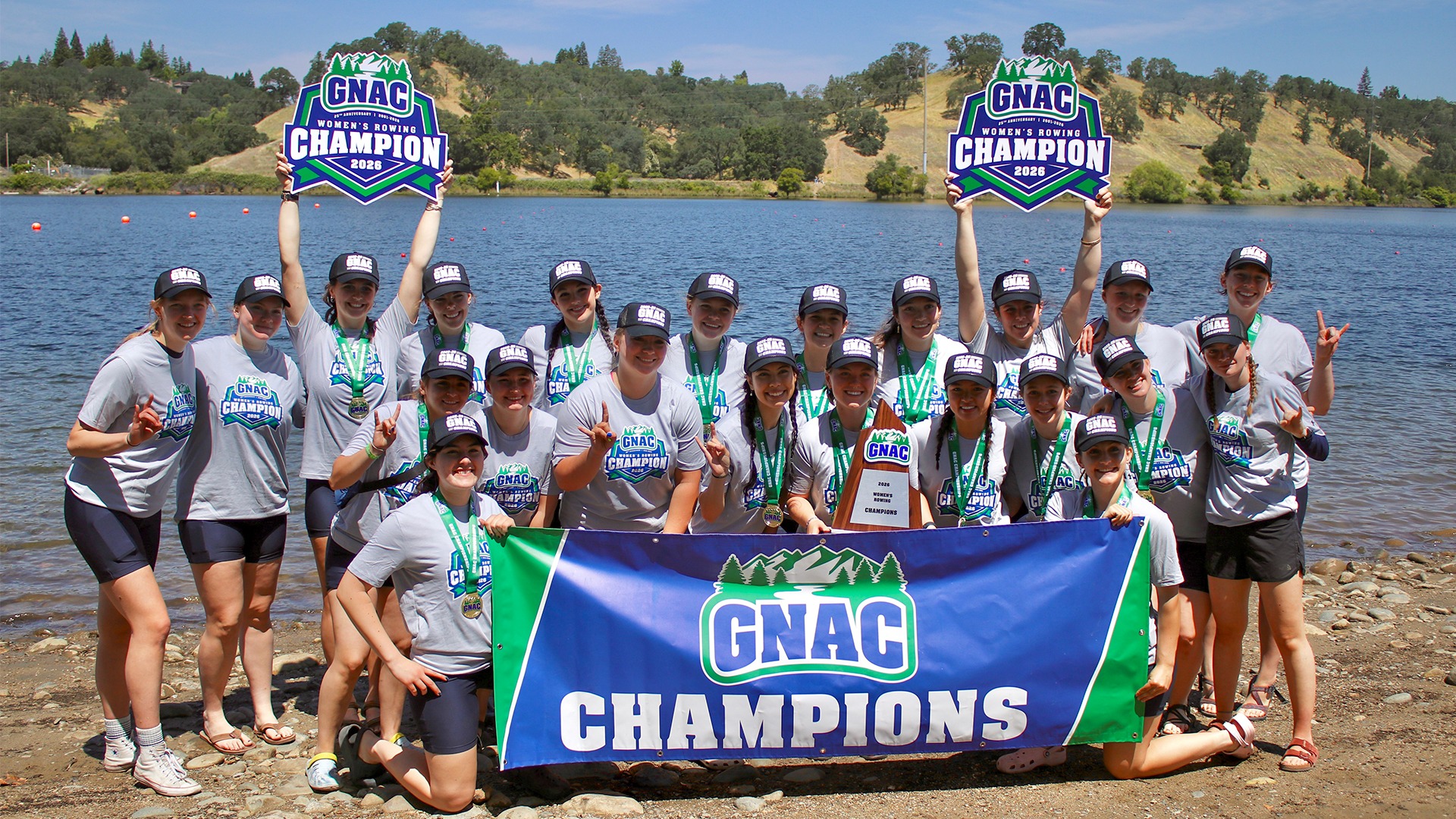 Team photo of WWU Rowing team on shores of Lake Natoma celebrating the conference championship