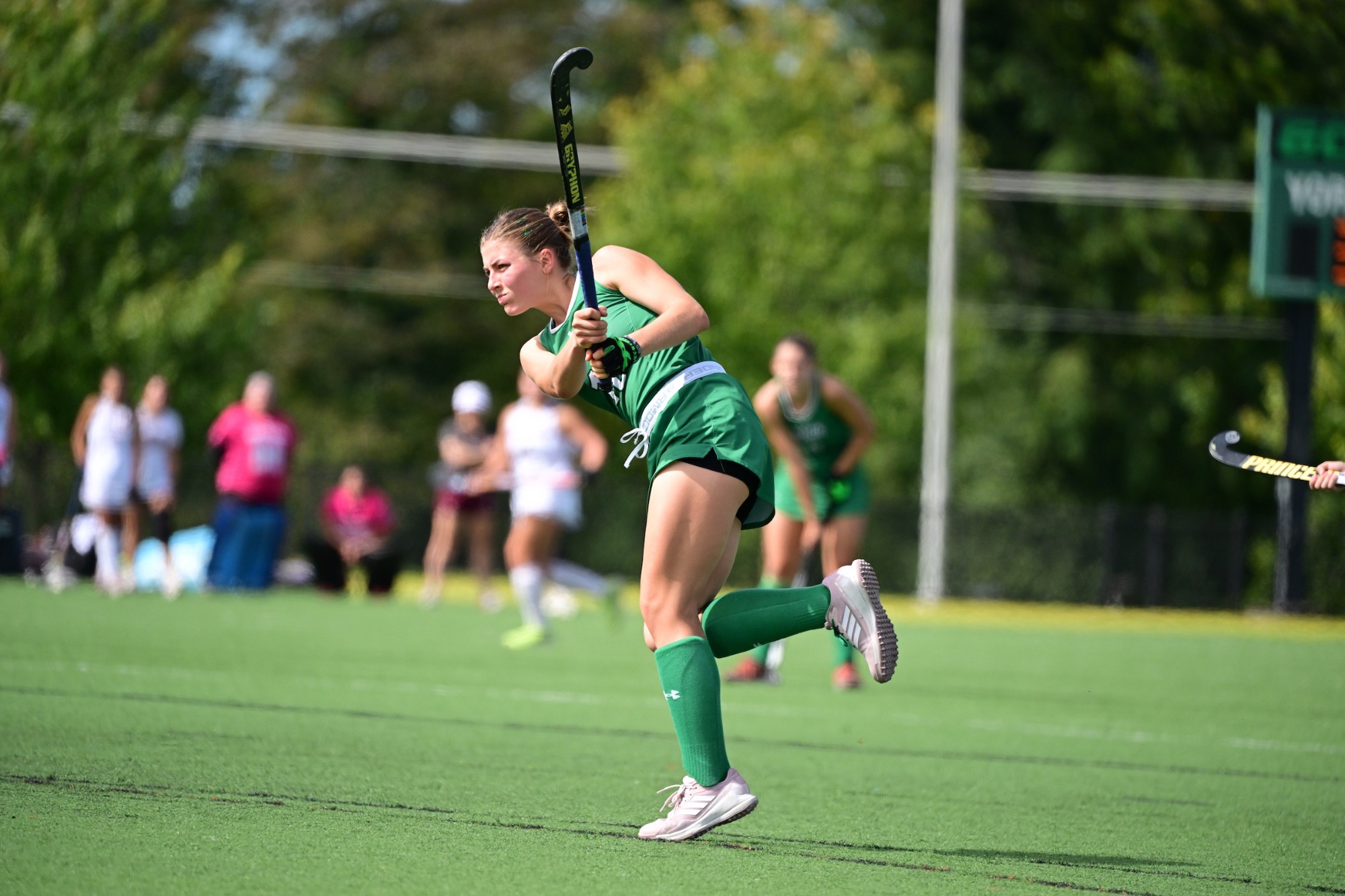Female hitting field hockey ball