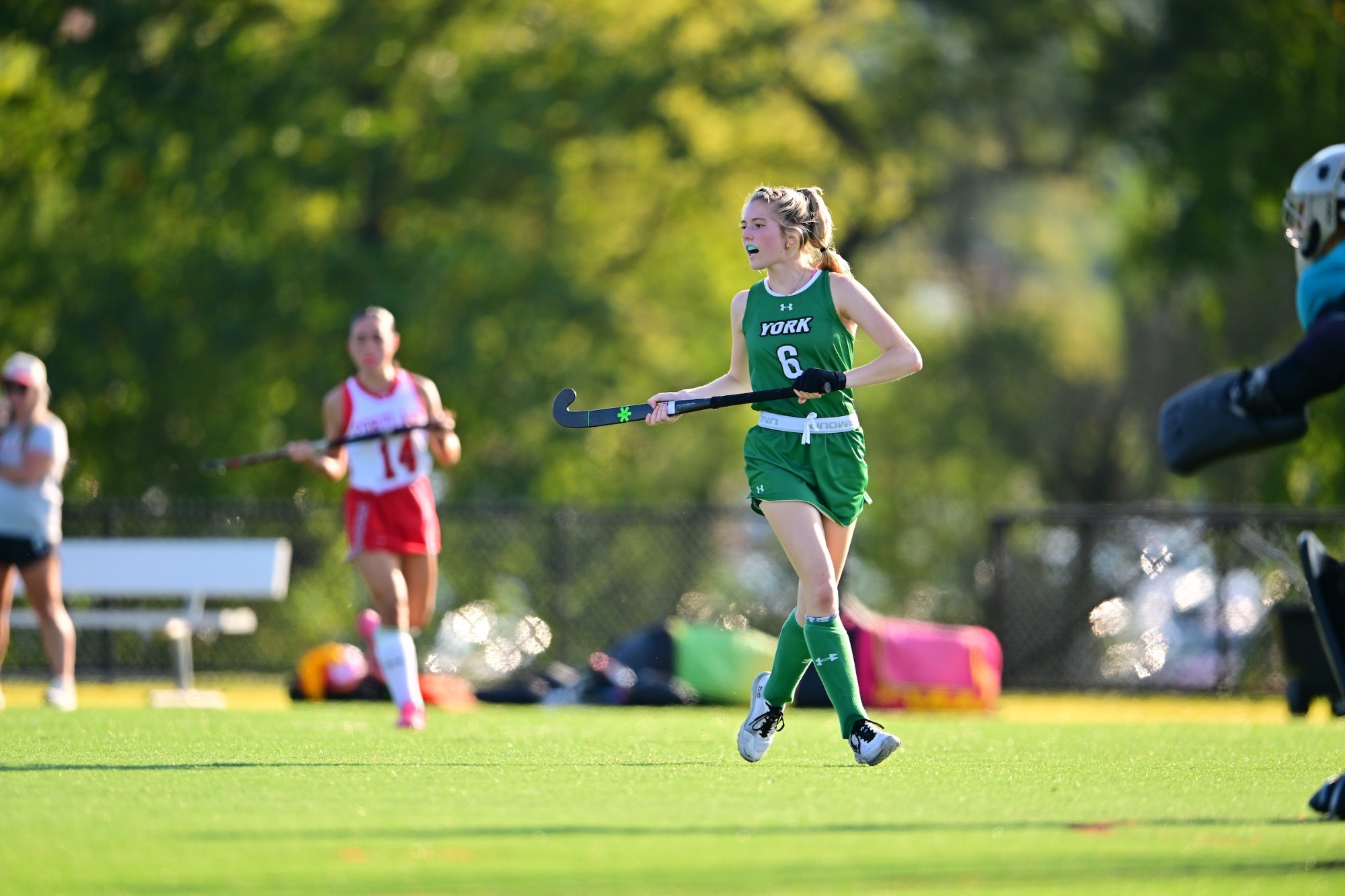 Female running with field hockey stick